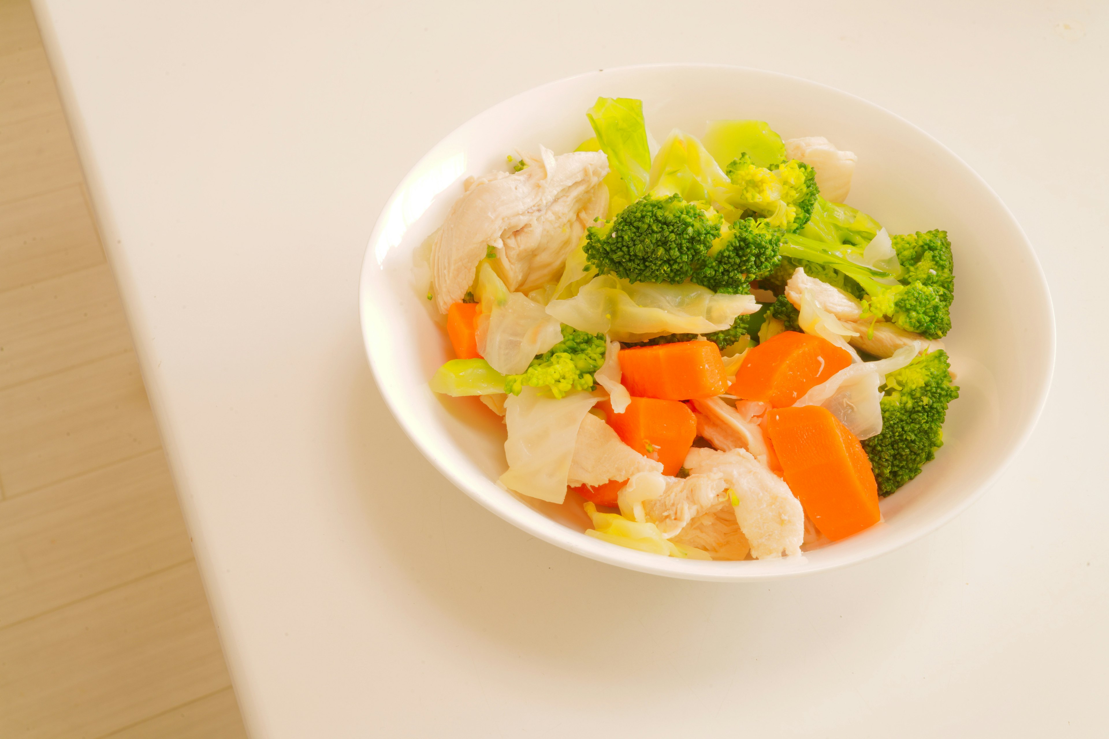 Chicken and vegetable salad featuring fresh broccoli, carrots, and lettuce in a bowl