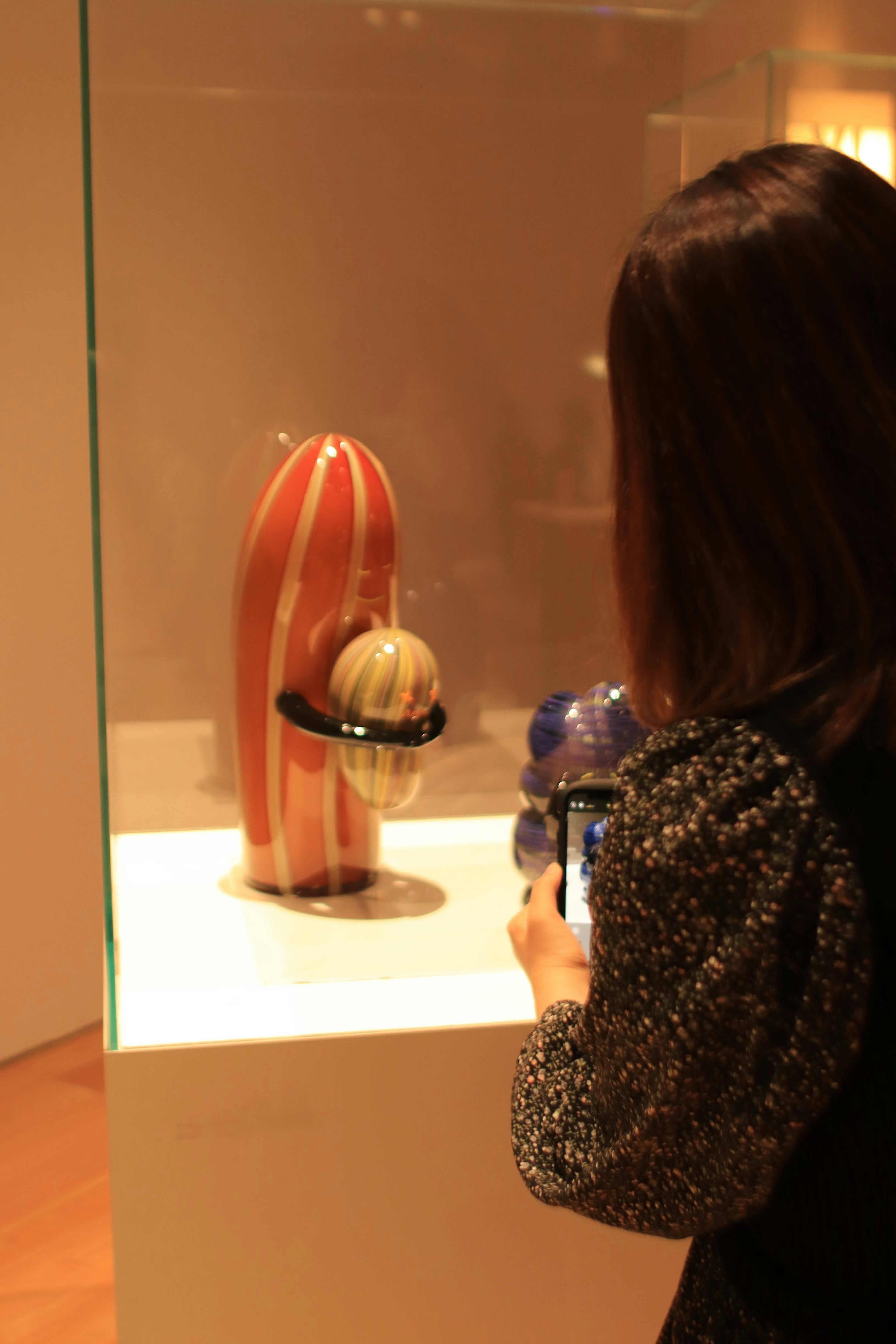 A woman photographing a unique art piece with vibrant colors and shapes