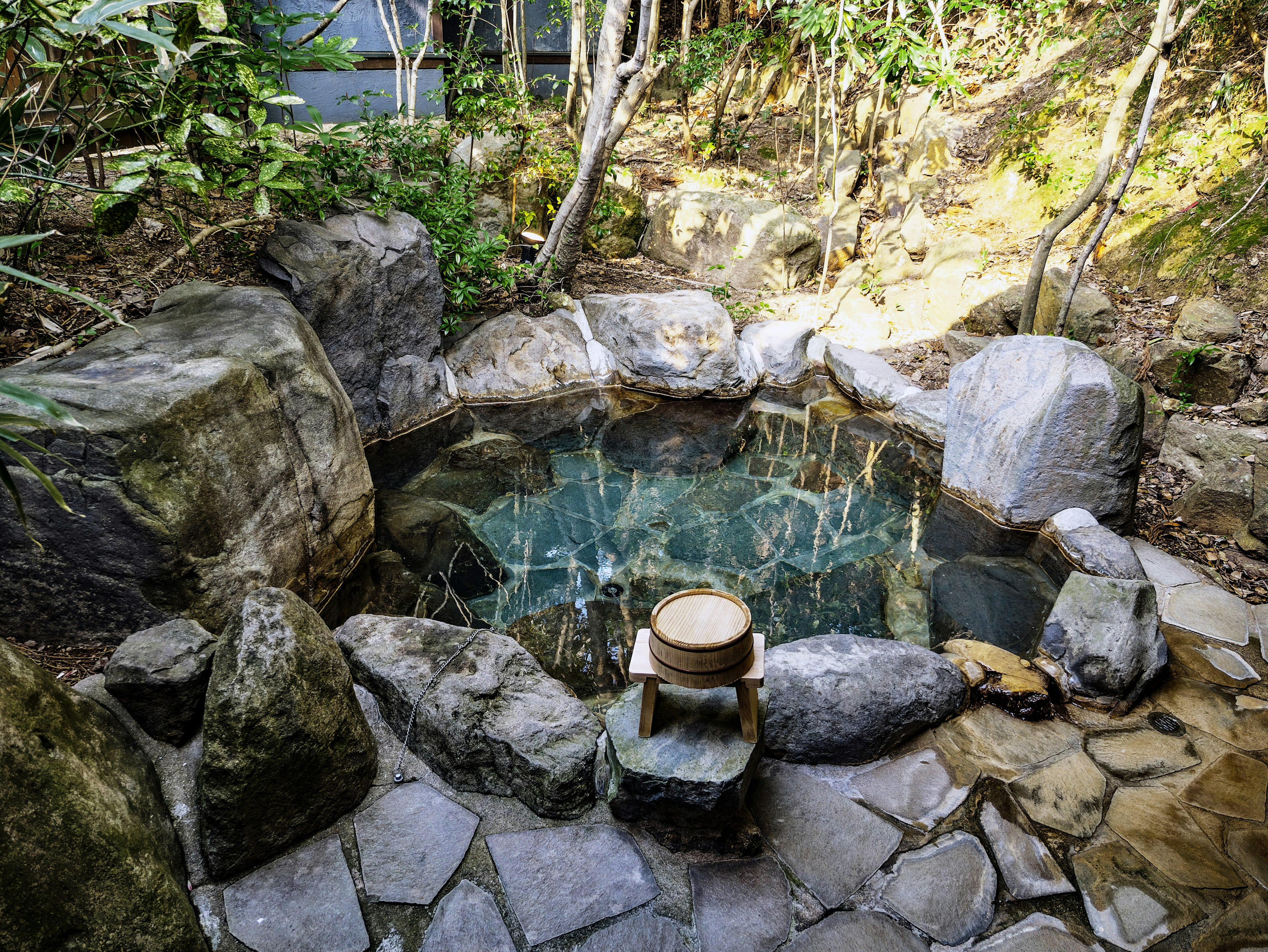 Scenic view of a hot spring surrounded by nature Large stones encircle the clear water creating a tranquil atmosphere