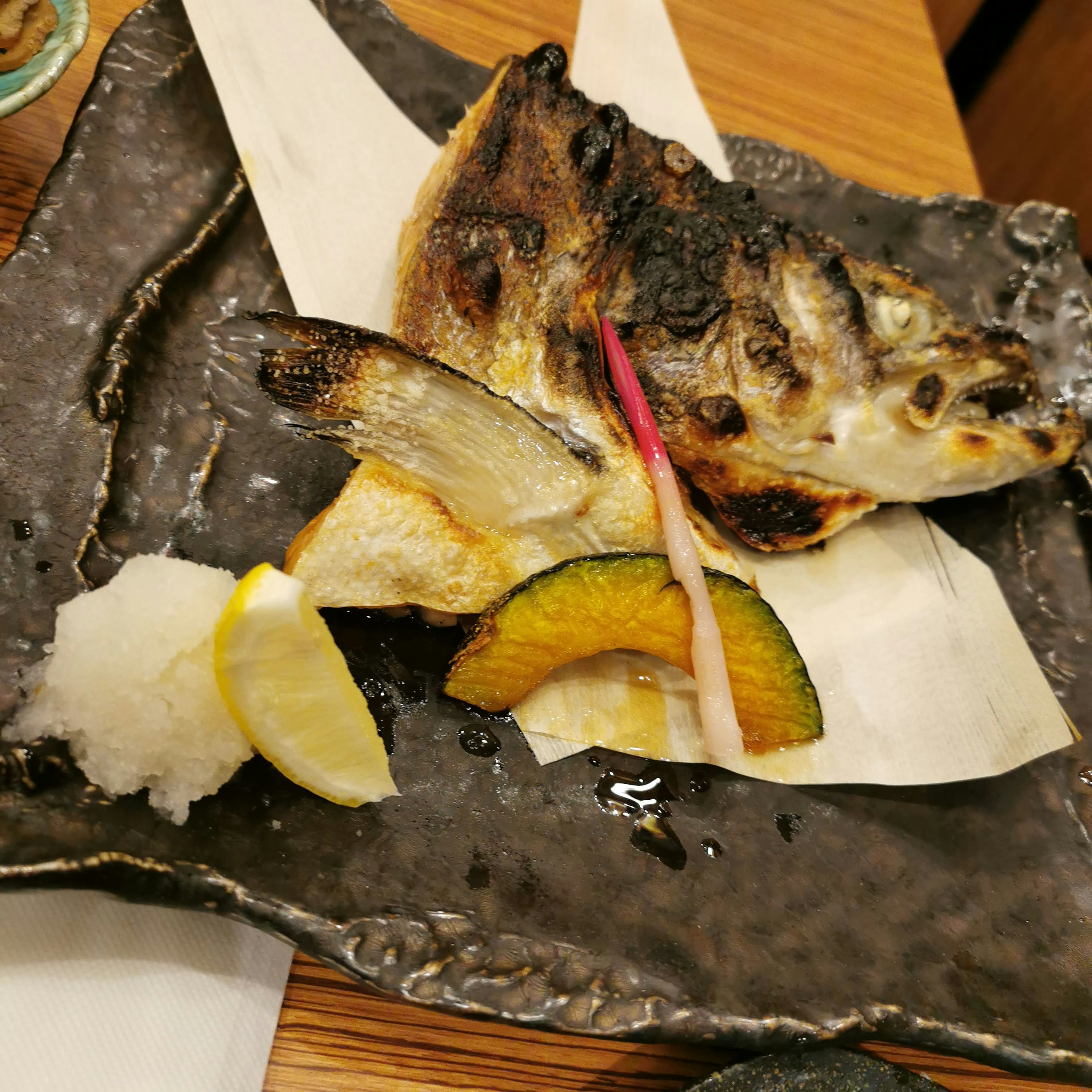 Grilled fish served with citrus and vegetables on a decorative plate