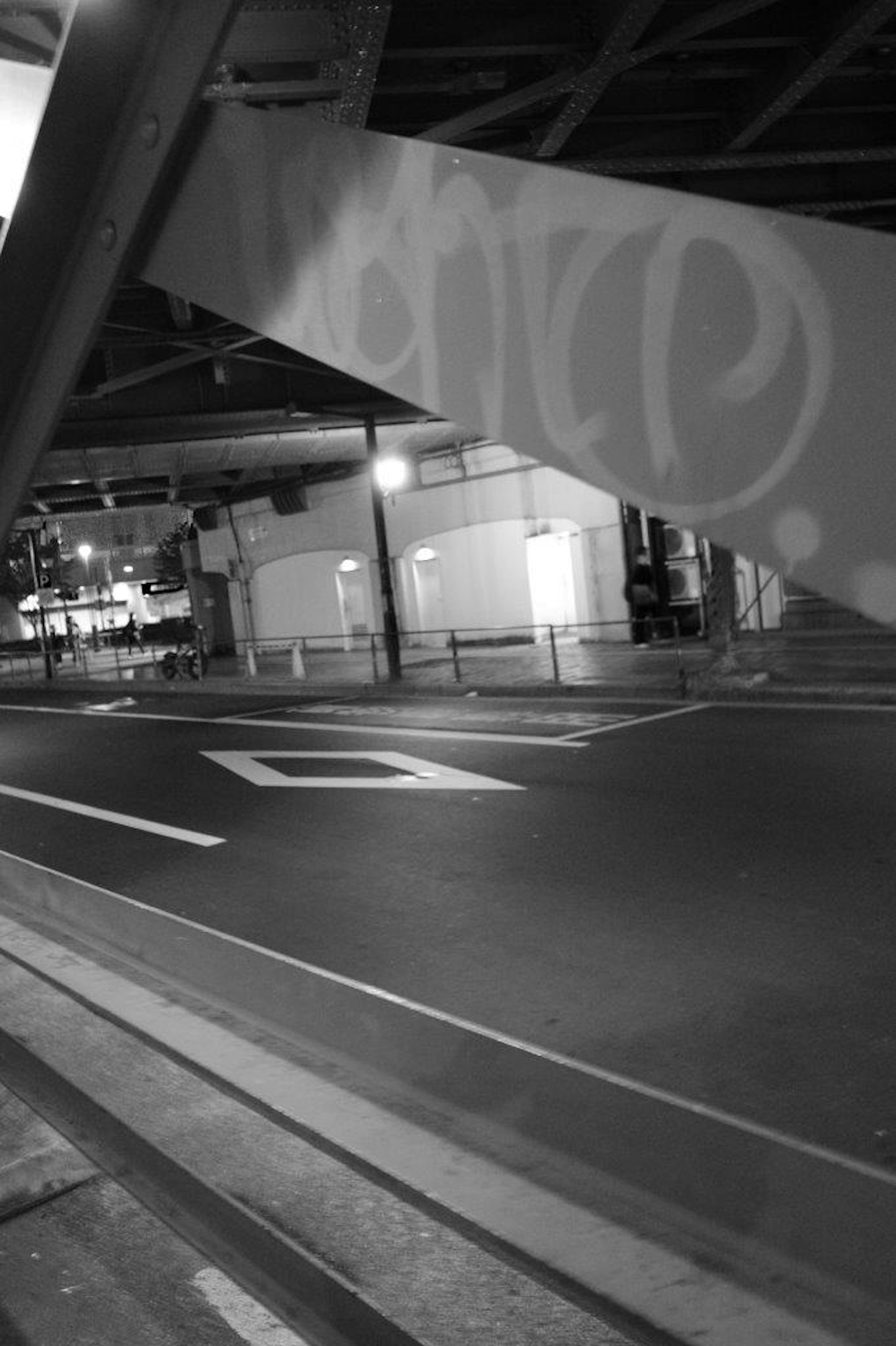 Black and white urban scene showing a street under a bridge