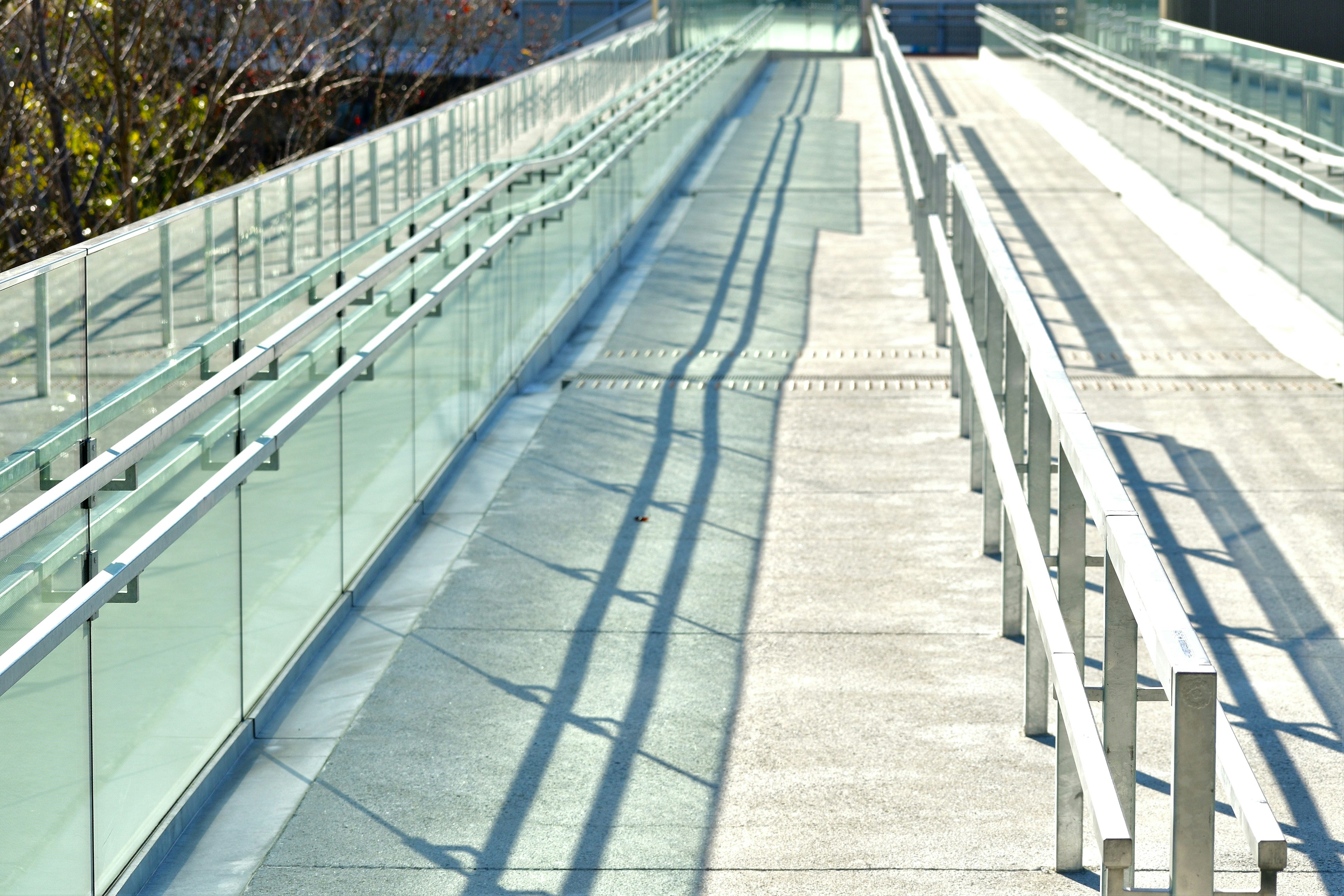 Modern walkway featuring glass railings and concrete slope