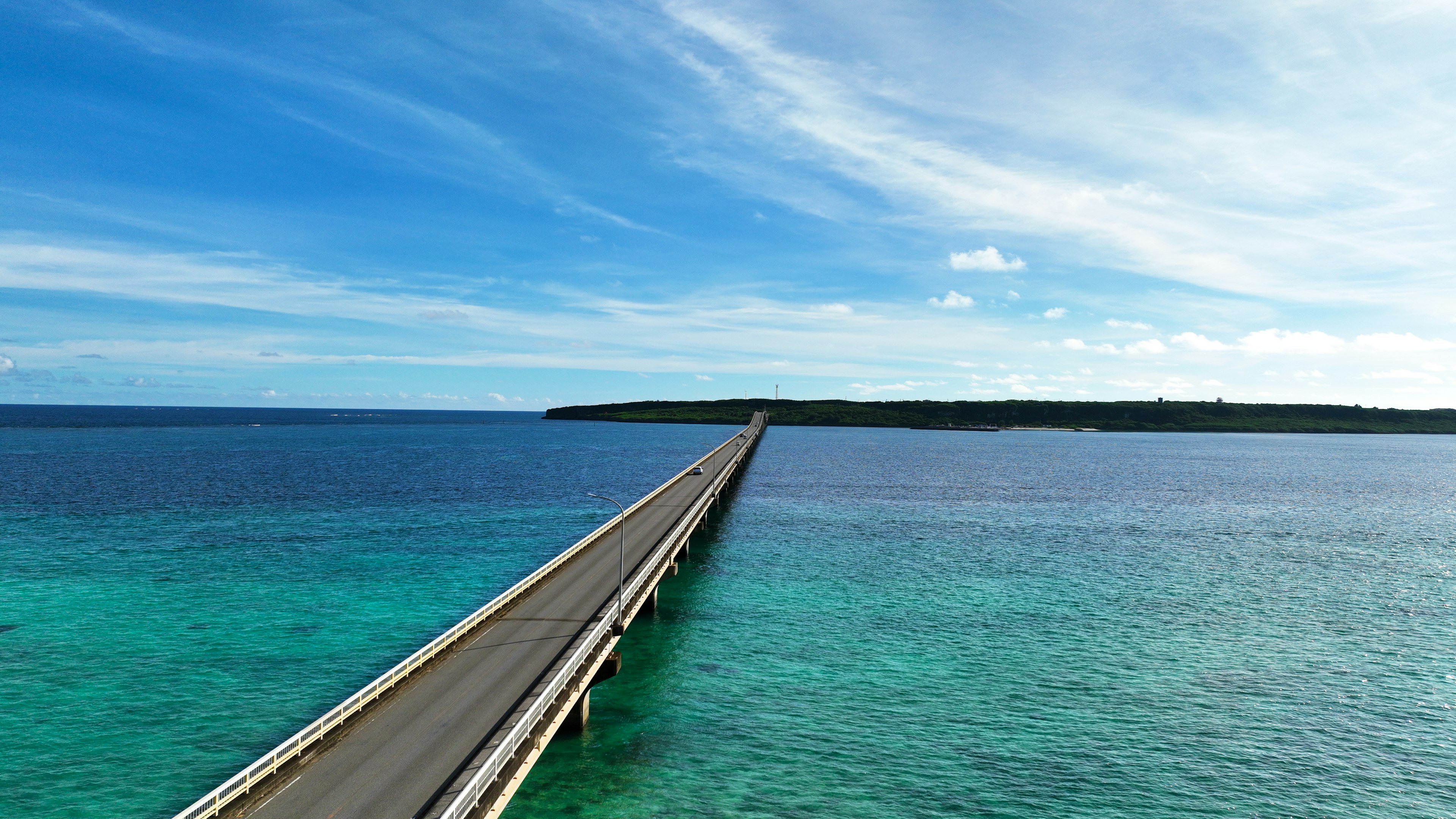 A long bridge extending over turquoise waters under a blue sky