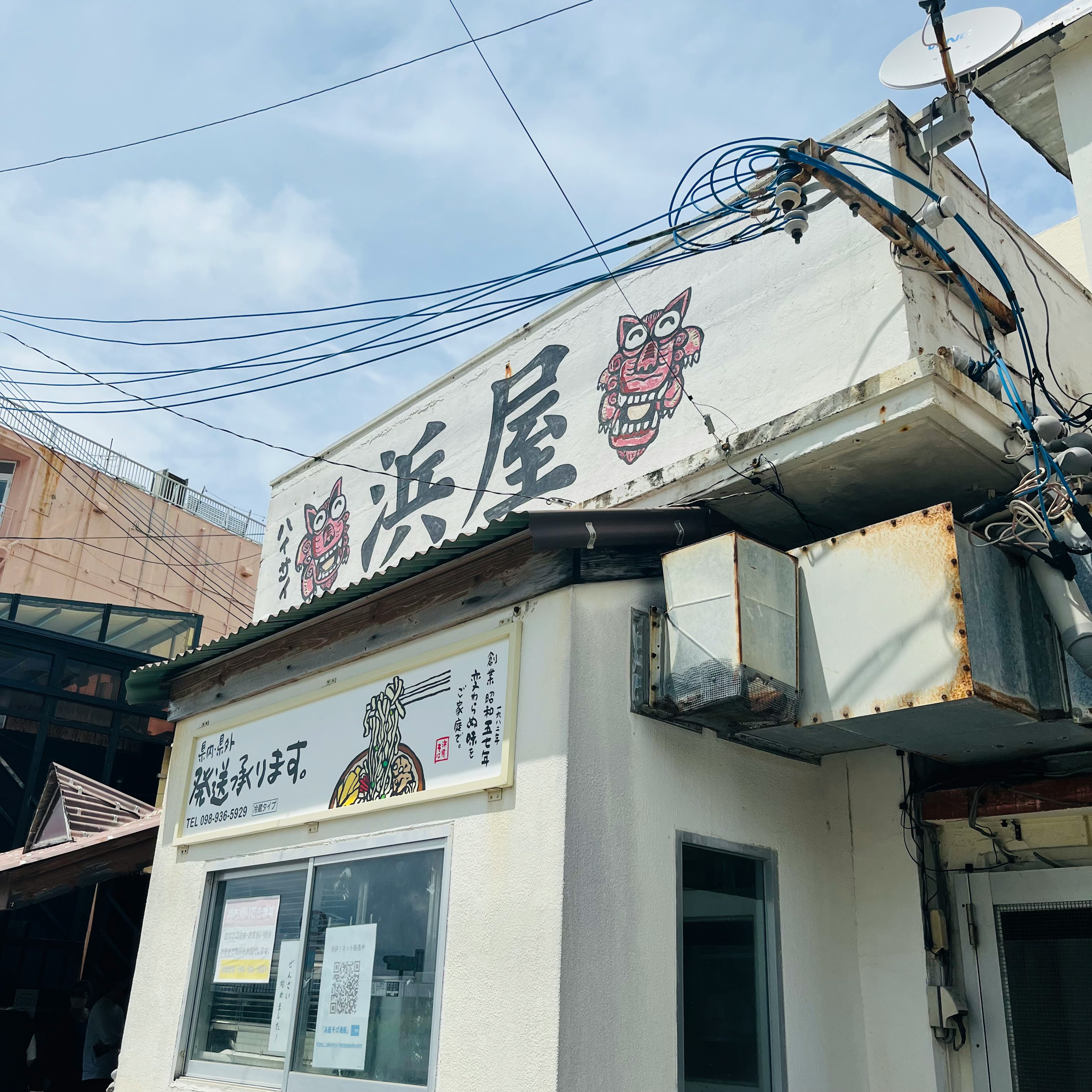 古い日本の飲食店の外観 白い壁に赤い文字の看板 電線が交差する空の下