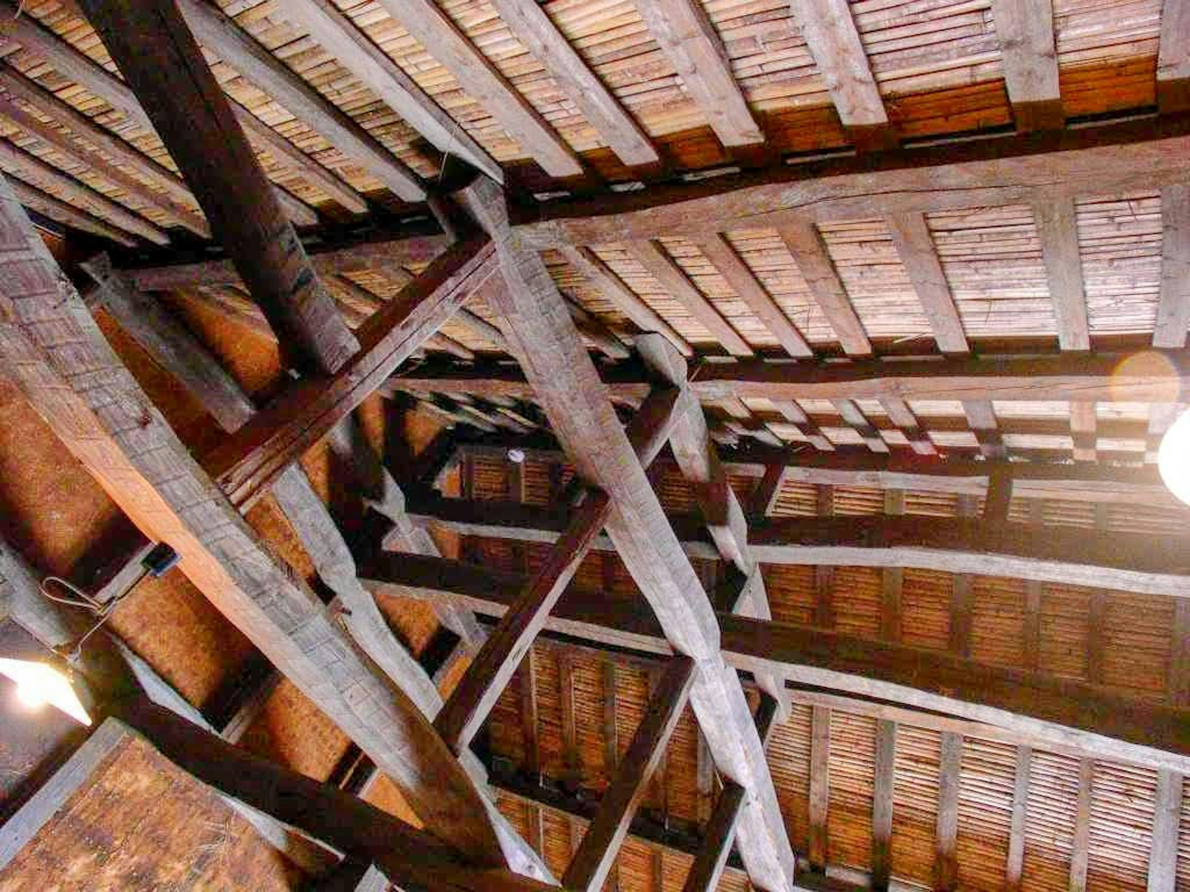 Image of a ceiling showcasing wooden beams and straw roof details