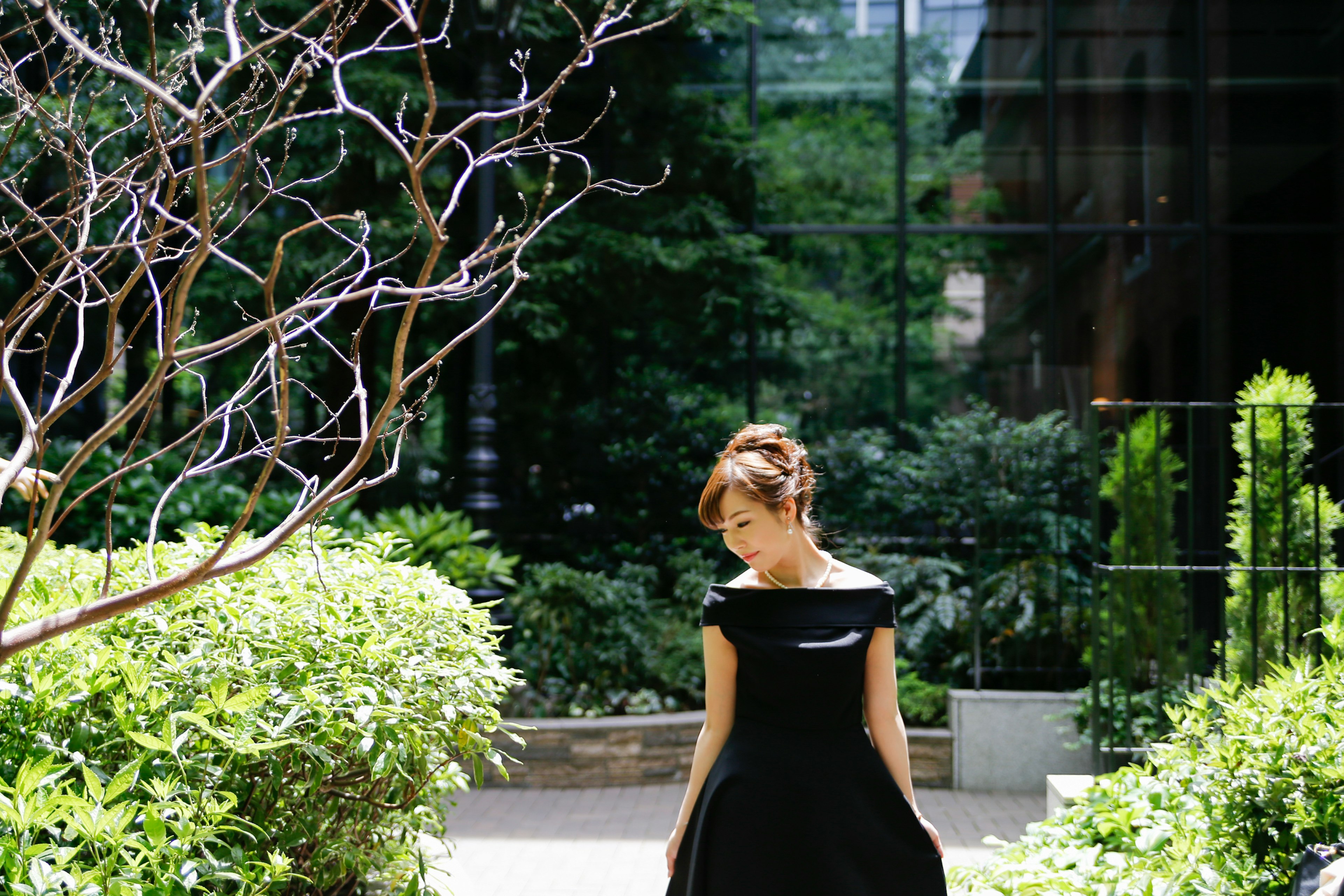 Une femme en robe noire se tenant dans un jardin entouré de verdure