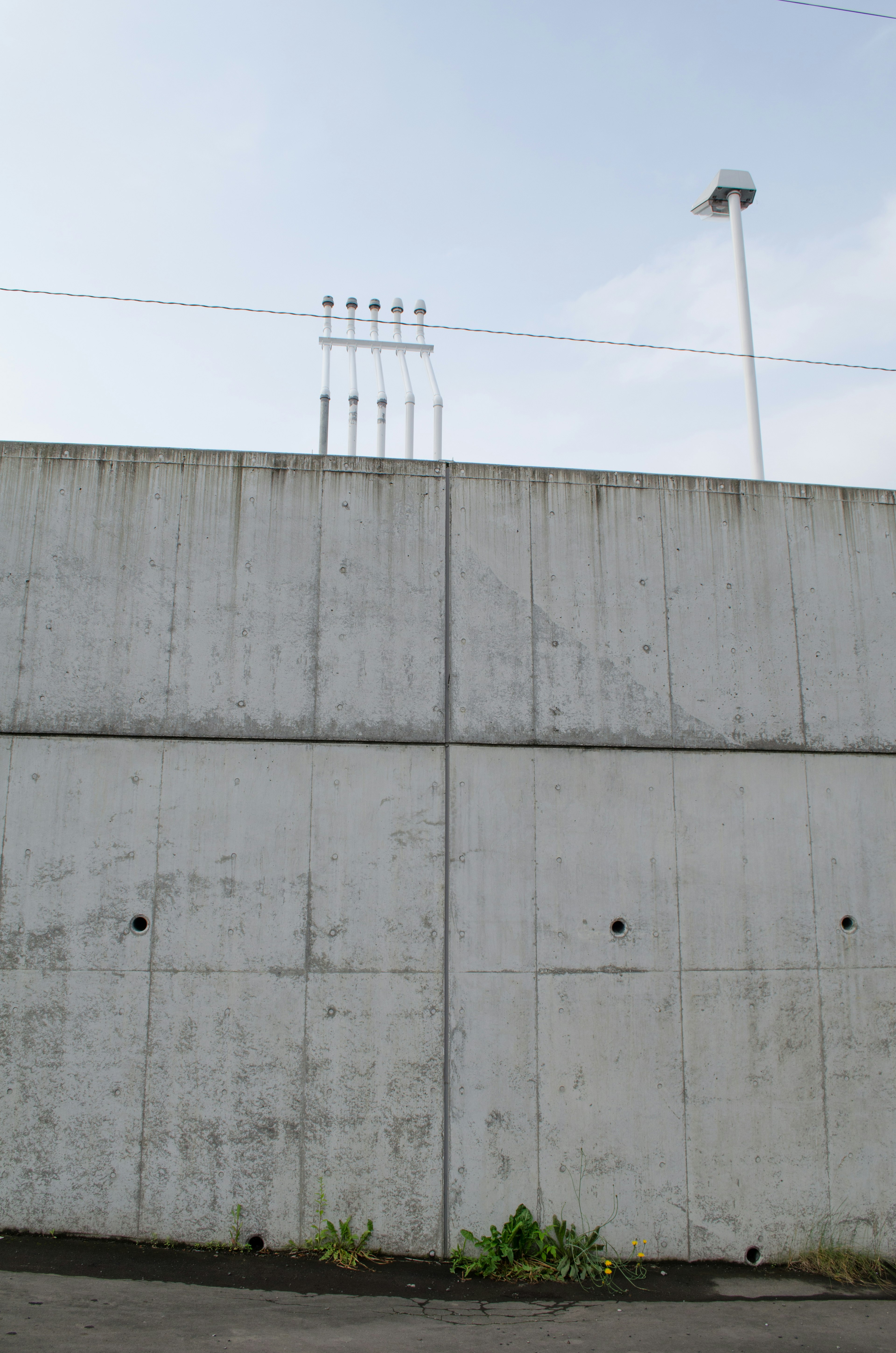 Concrete wall with lighting poles and power lines above