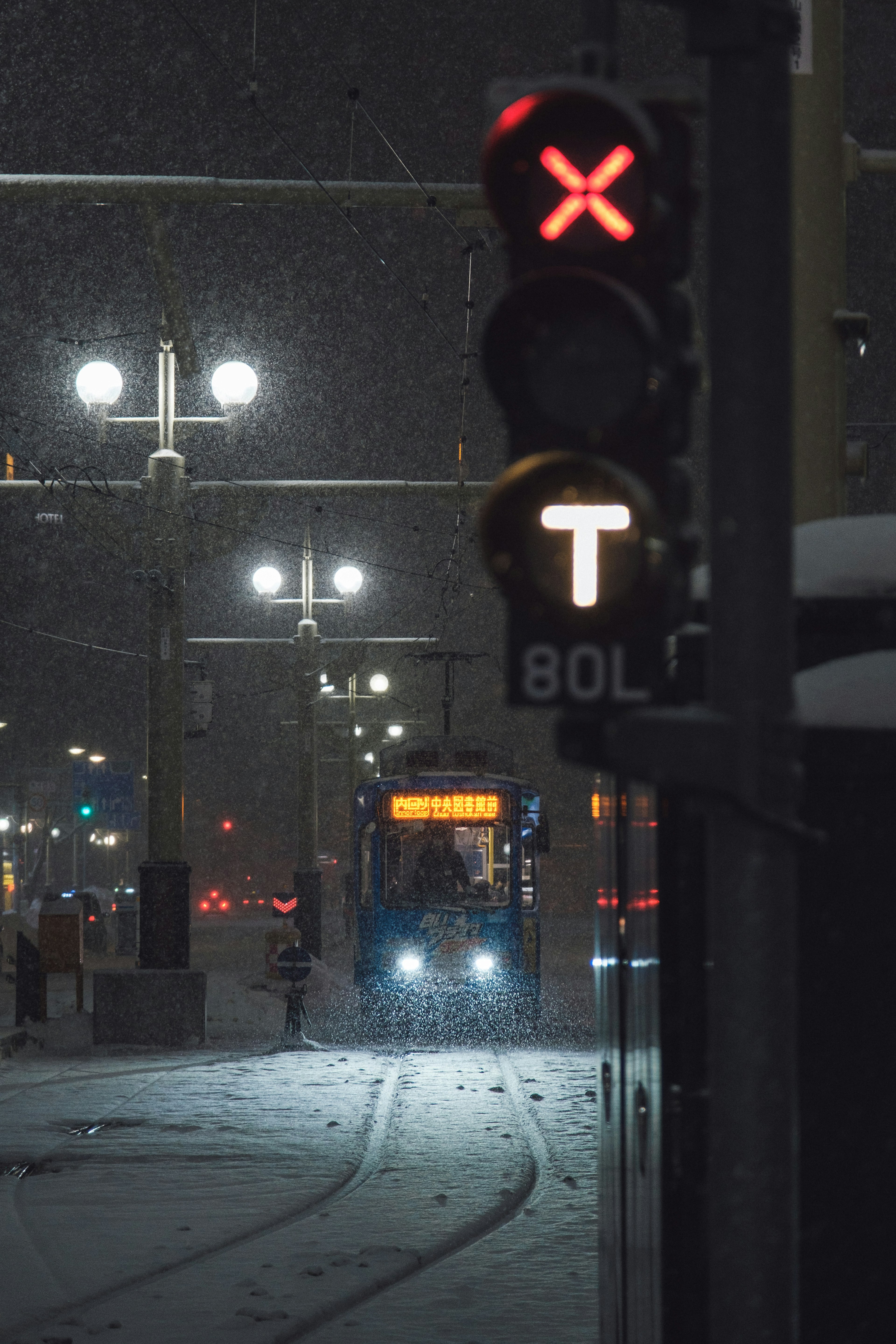 Verkehrssignale im Schnee mit einer herannahenden Straßenbahn