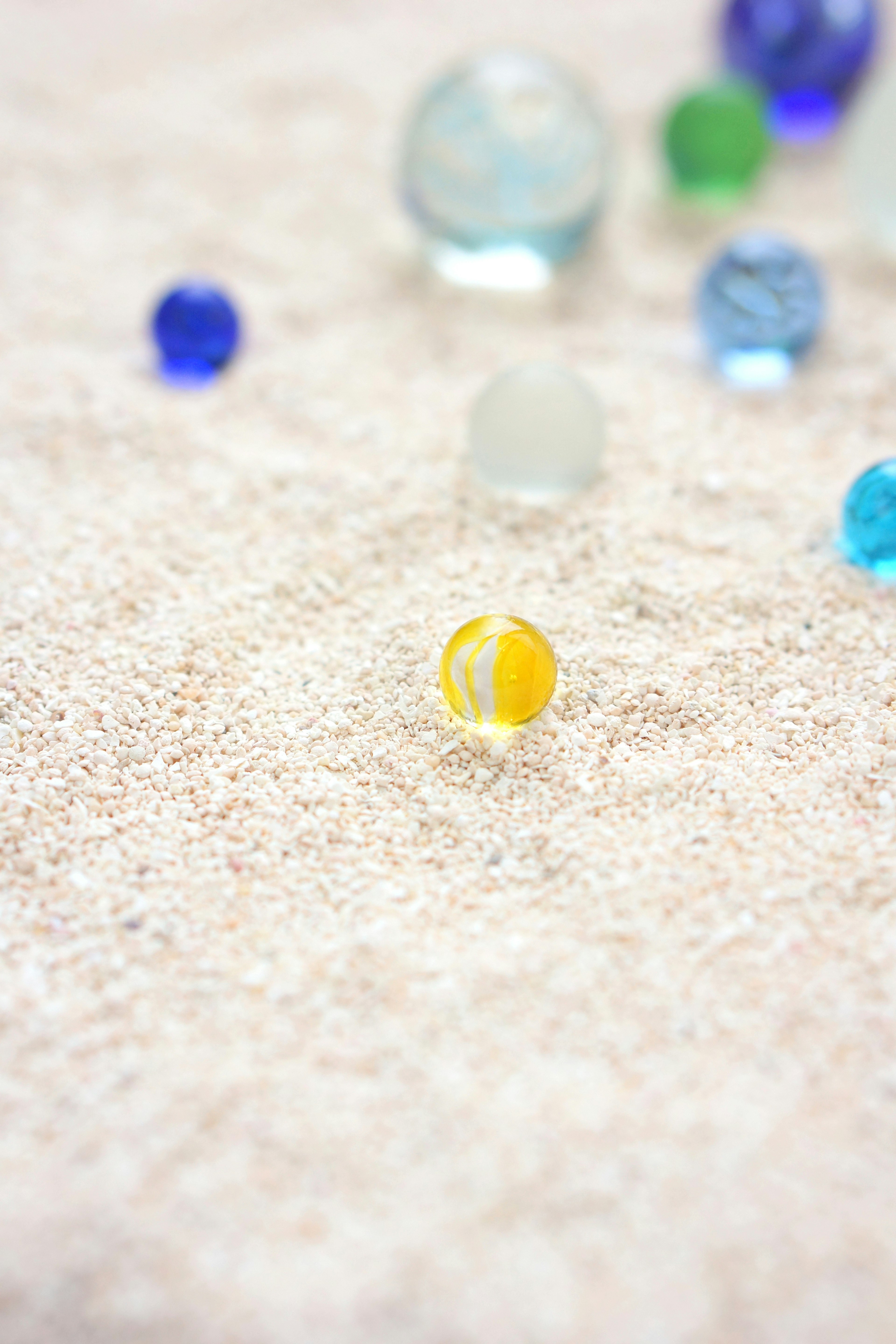 Colorful marbles scattered on sandy surface