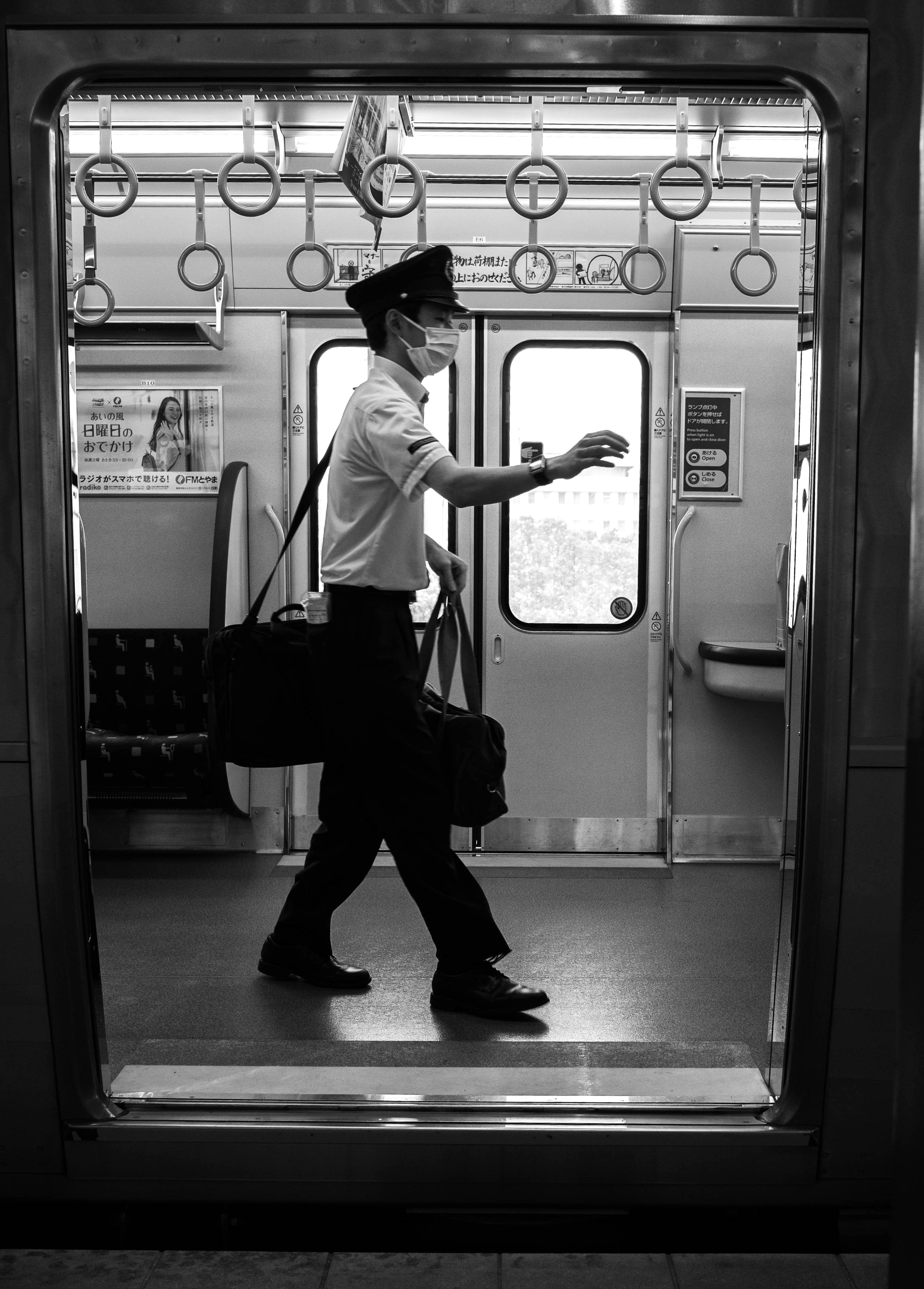 Image en noir et blanc d'un conducteur de train marchant devant une porte de train