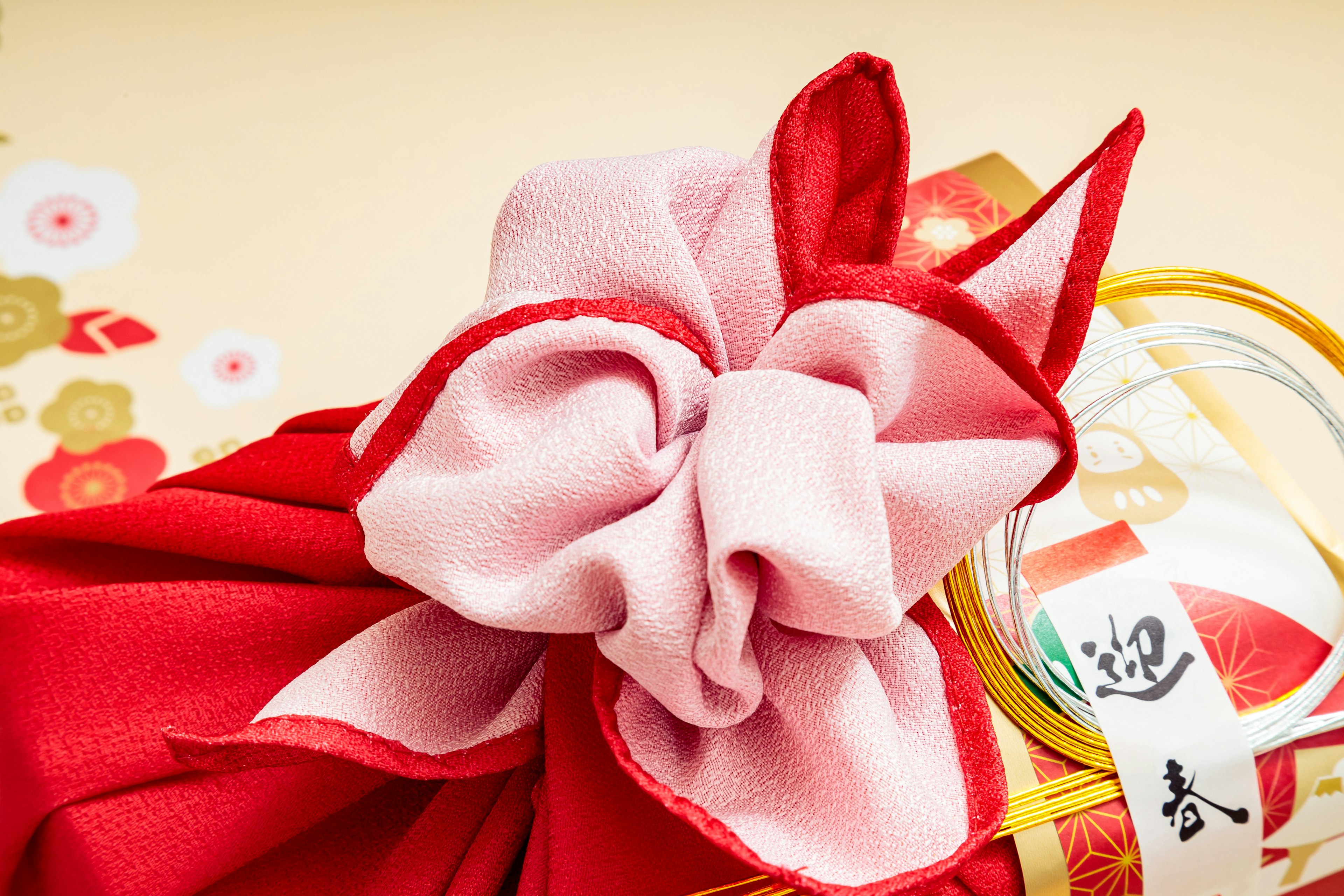 Traditional Japanese wrapping featuring a red cloth and a pink ribbon