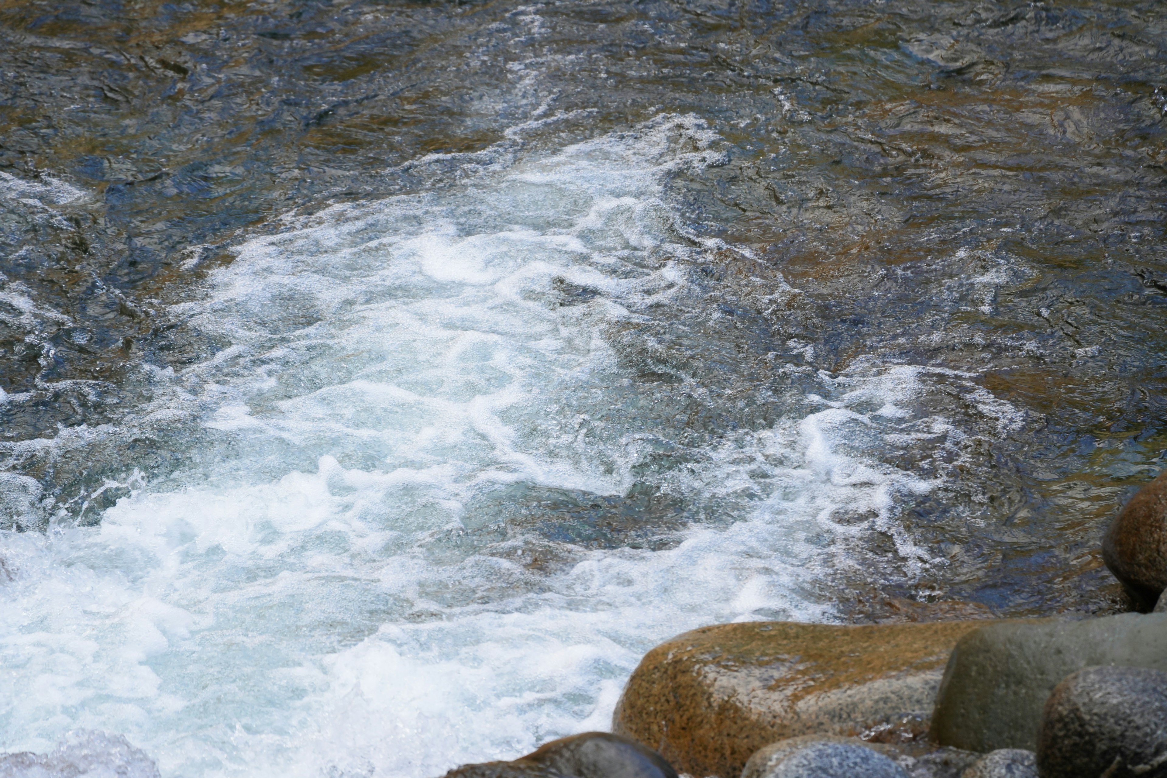 Agua fluyendo con rocas en primer plano