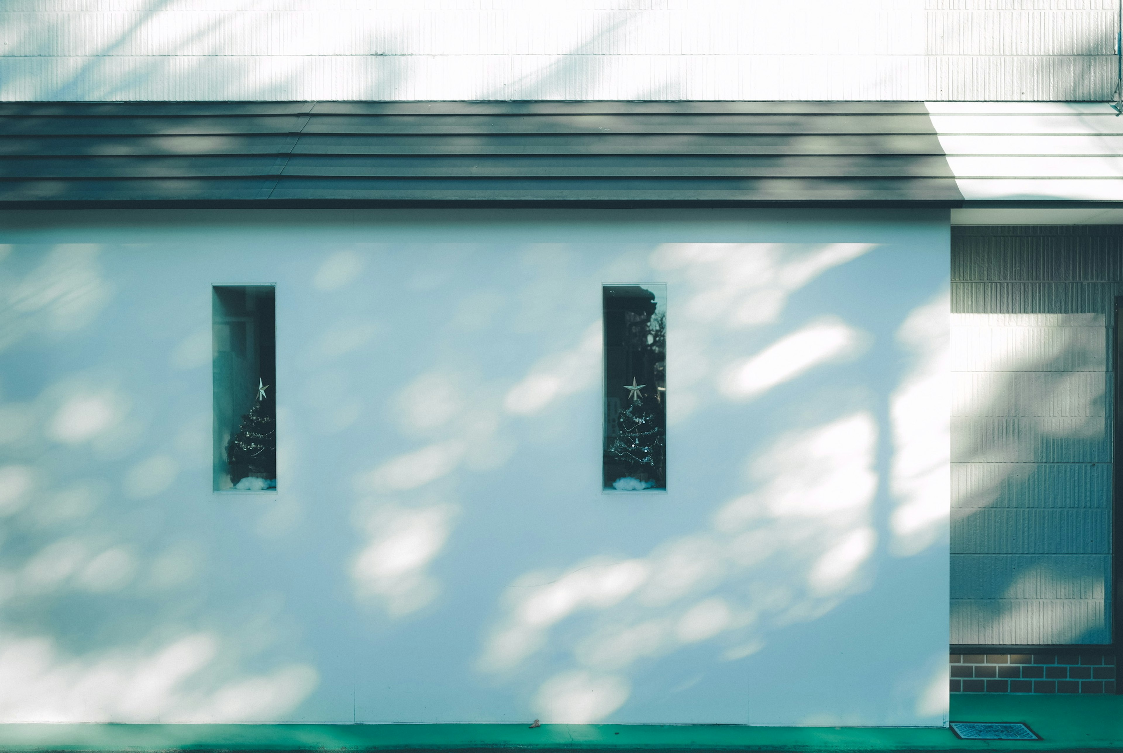 Mur blanc avec trois fenêtres projetant des ombres