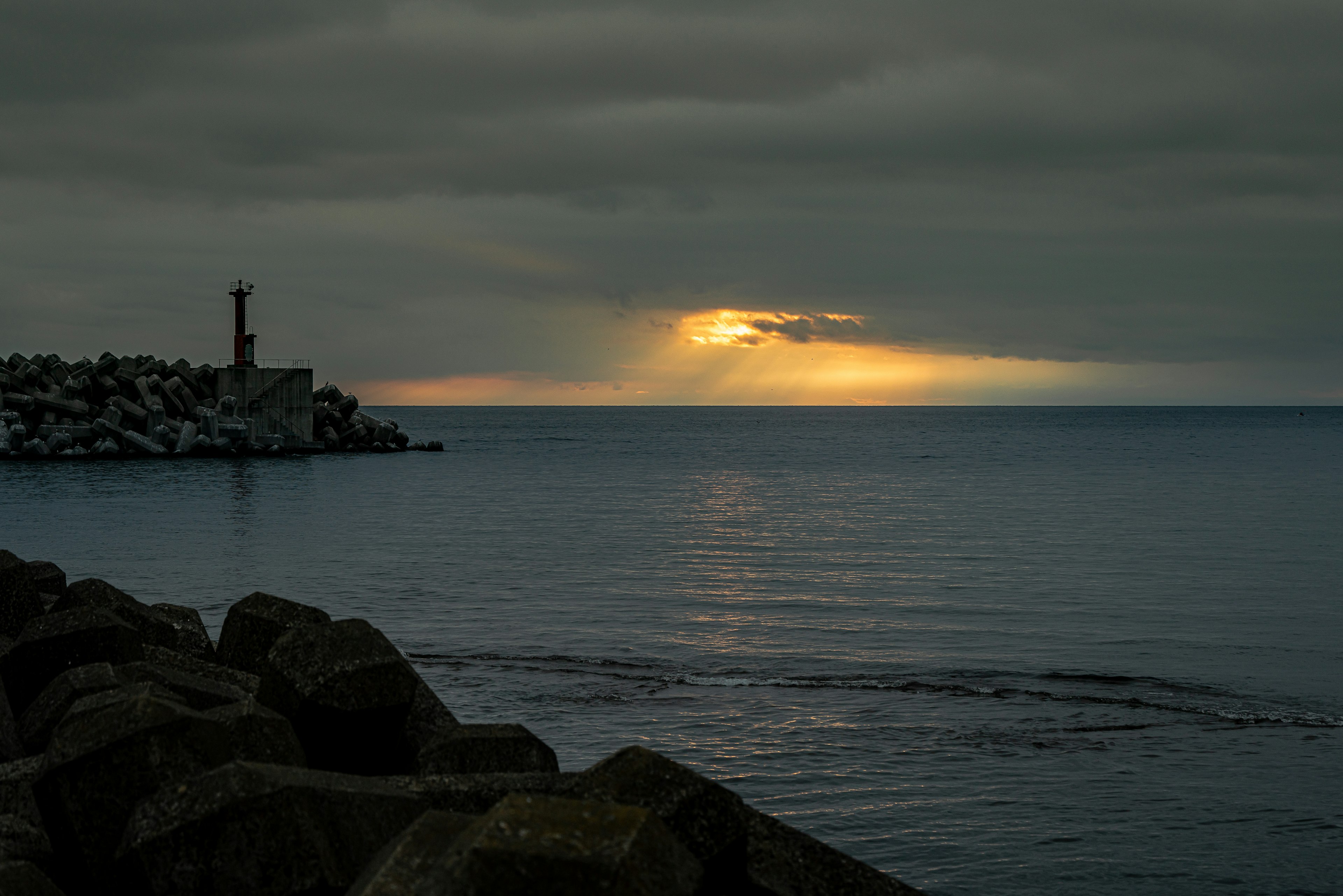 Una vista di un mare scuro con un faro illuminato da una luce tenue