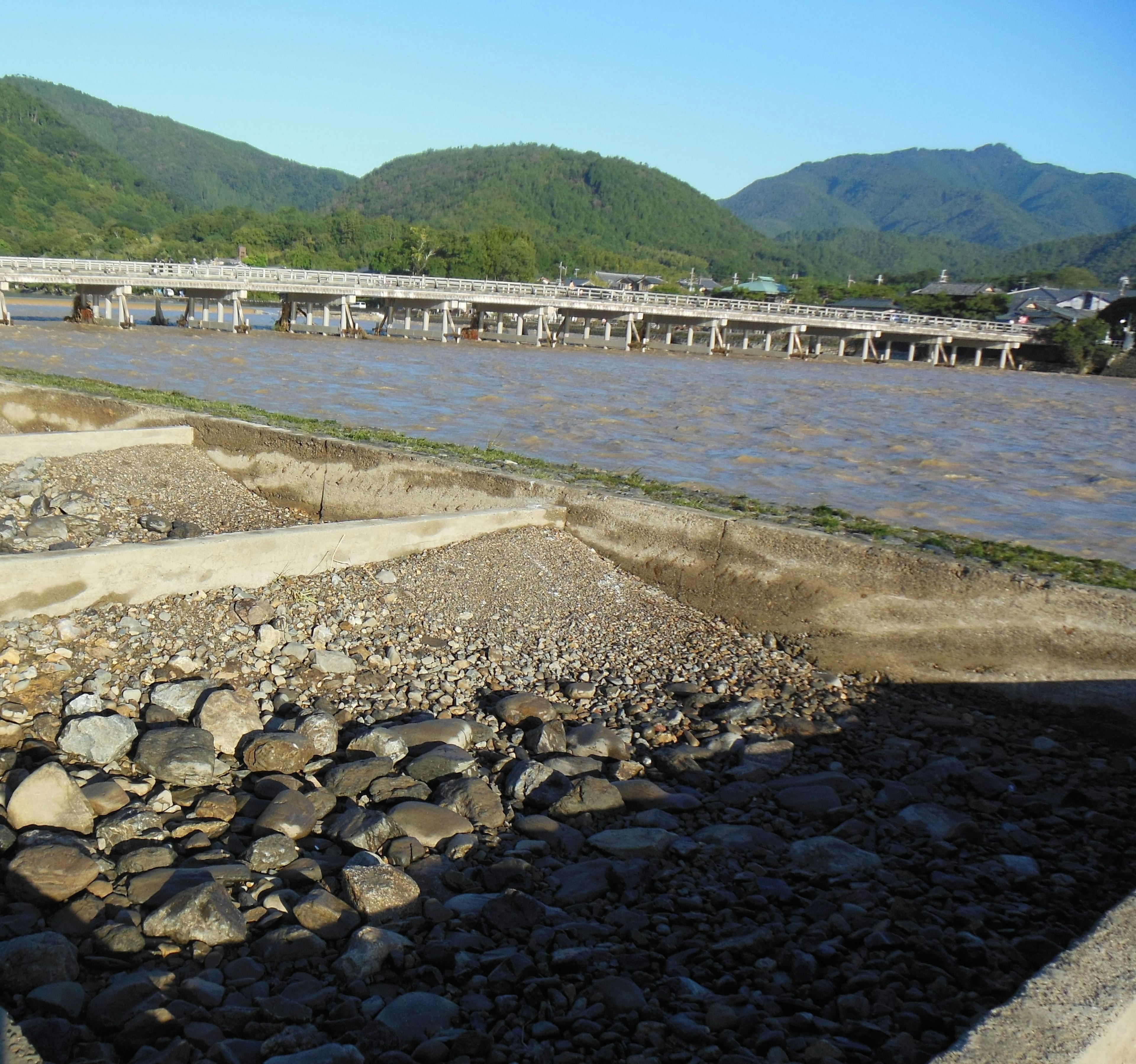 Scène de rivière avec de l'eau qui s'écoule et un pont montagnes vertes en arrière-plan