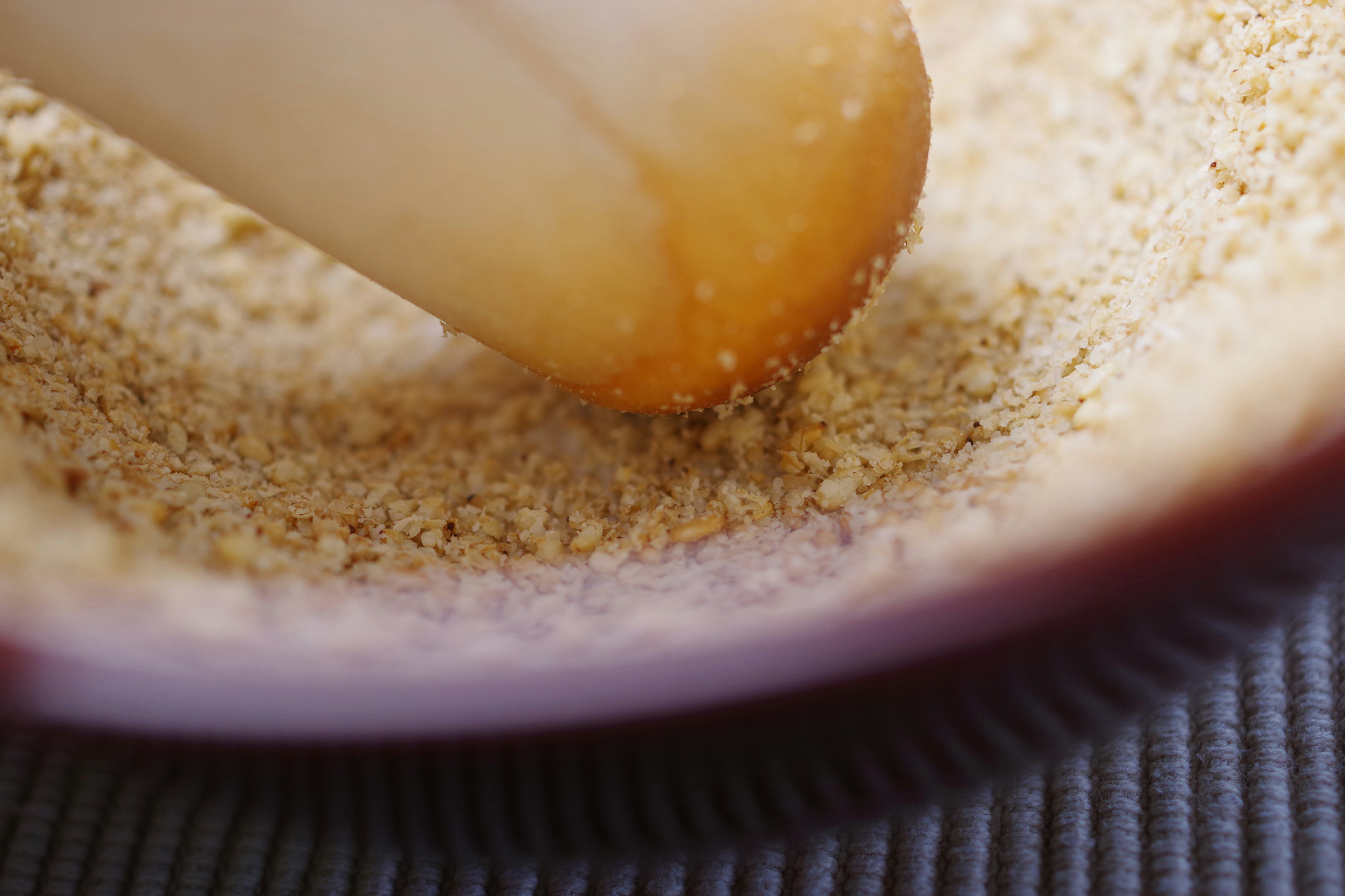 Close-up of a wooden pestle grinding ingredients in a bowl