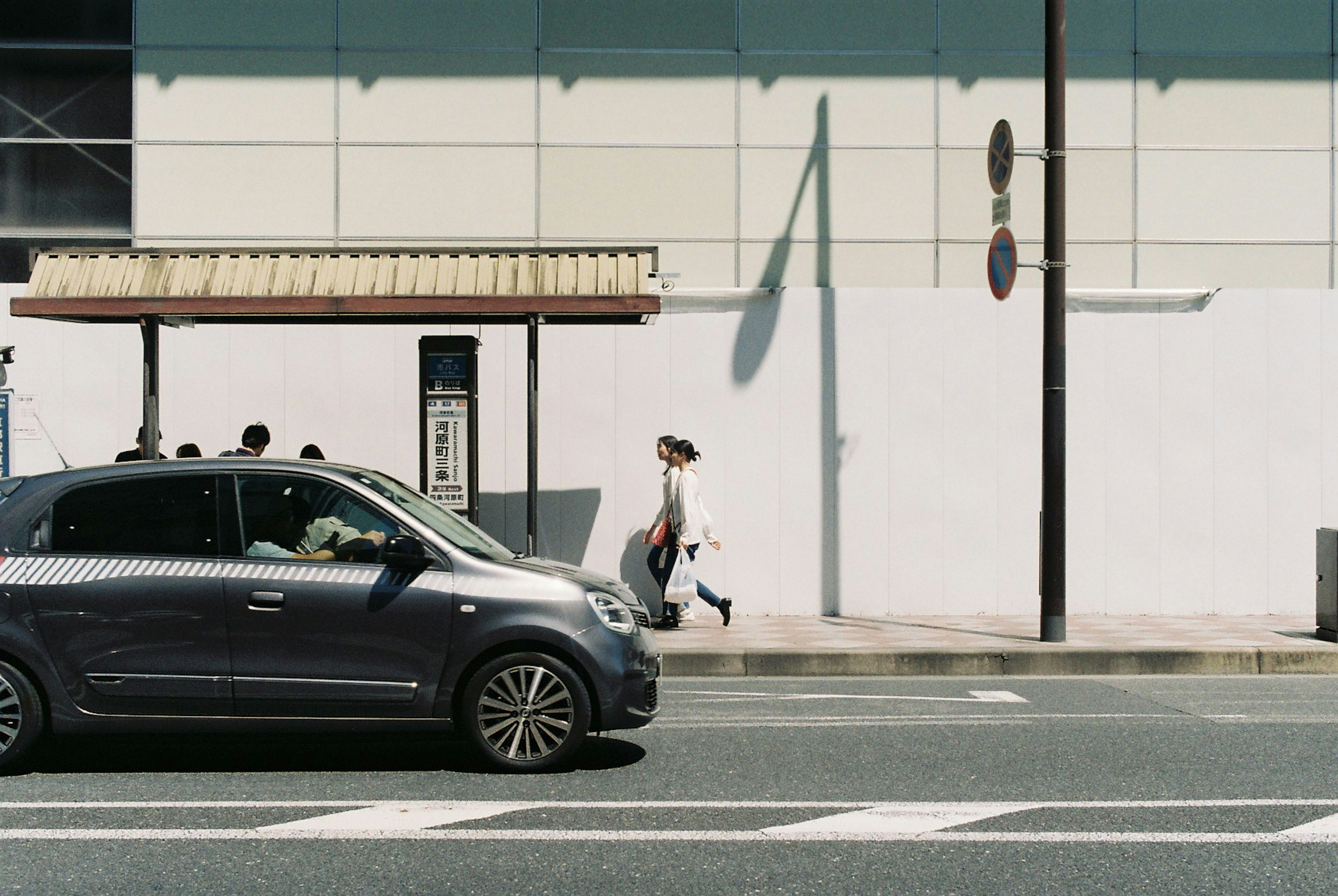 A person walking along the street next to a passing car