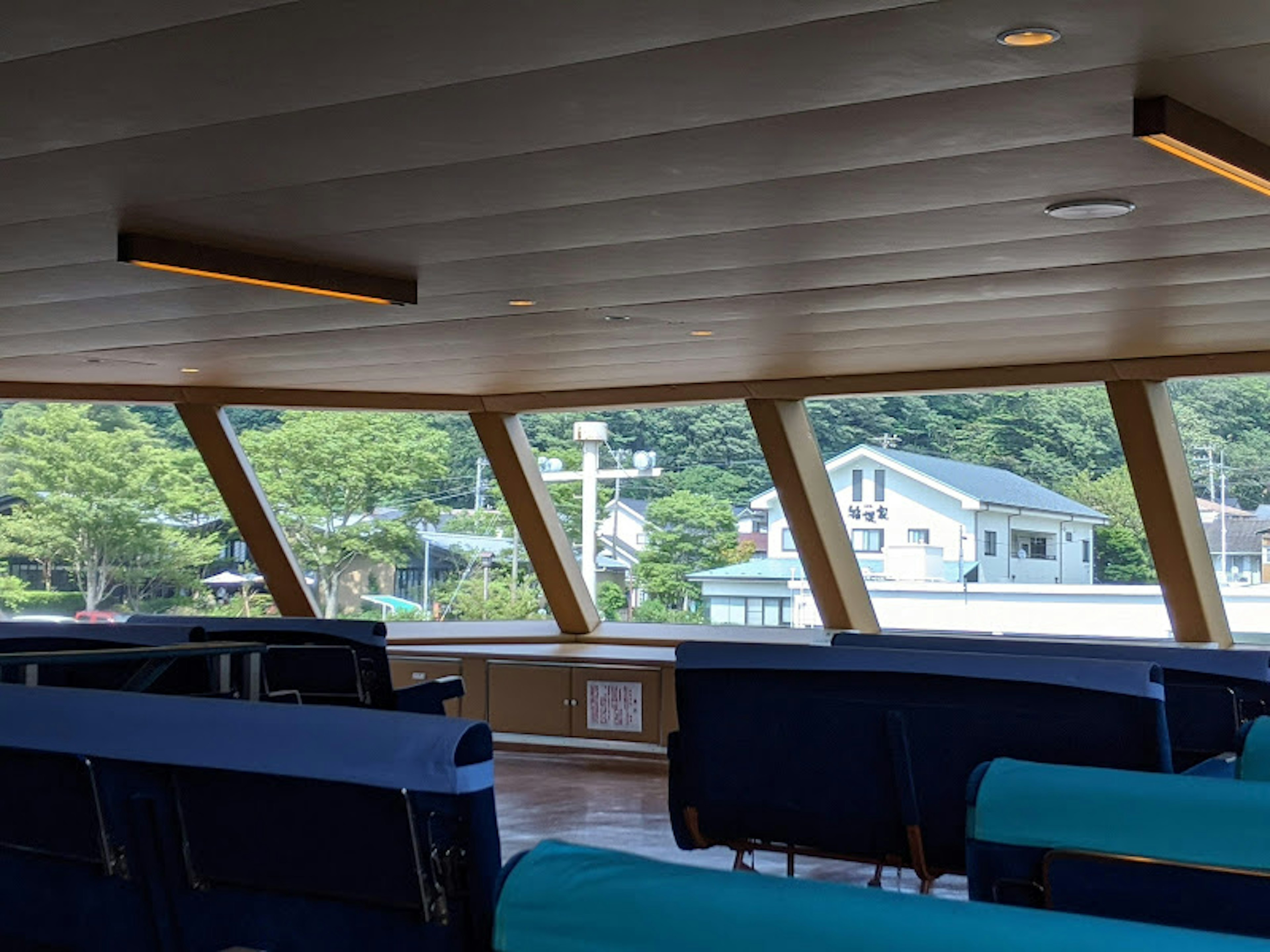 Vue de l'intérieur d'un bateau avec de grandes fenêtres et des maisons visibles à l'extérieur