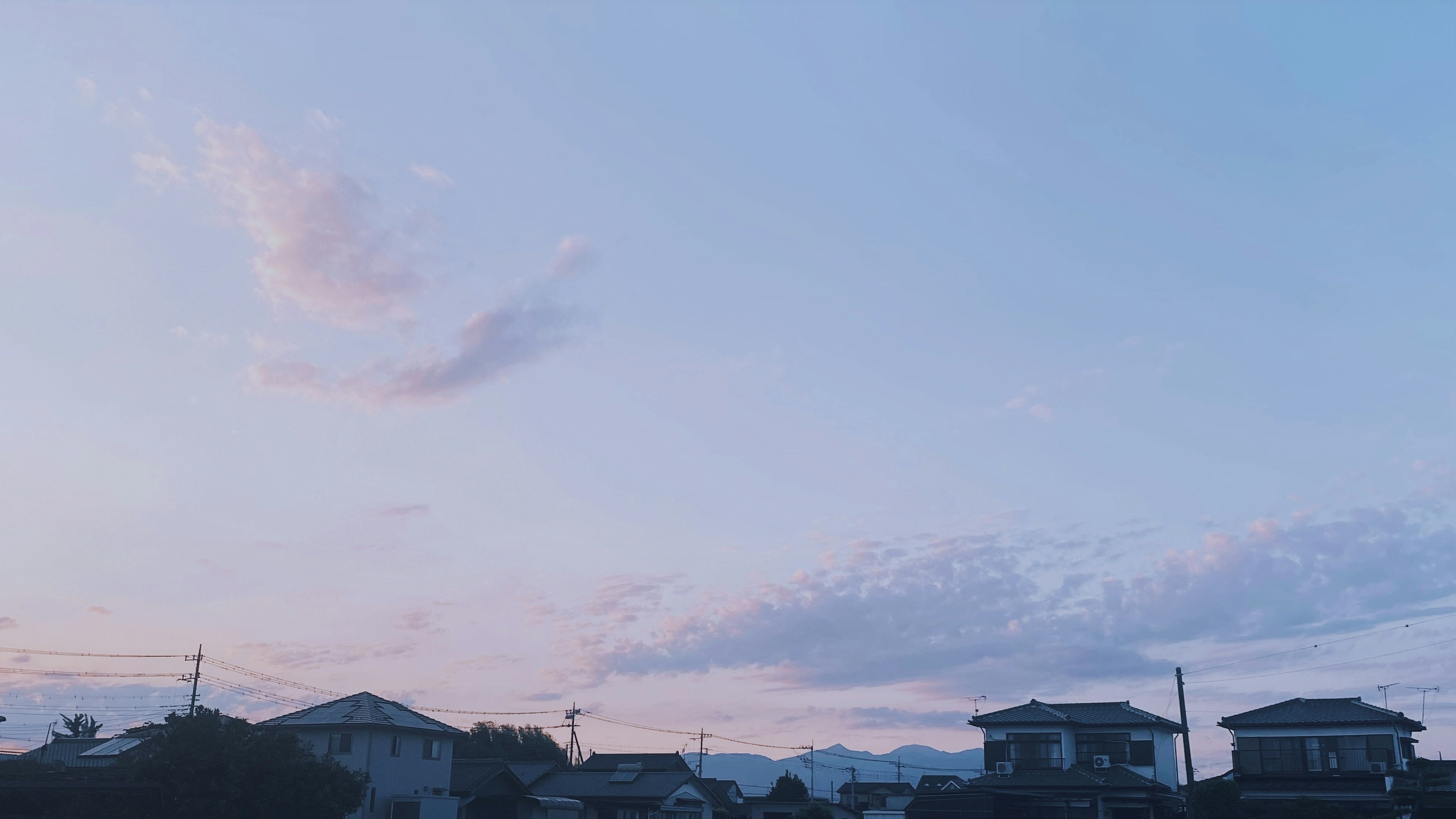 Ciel crépusculaire avec des nuages doux et des silhouettes de maisons