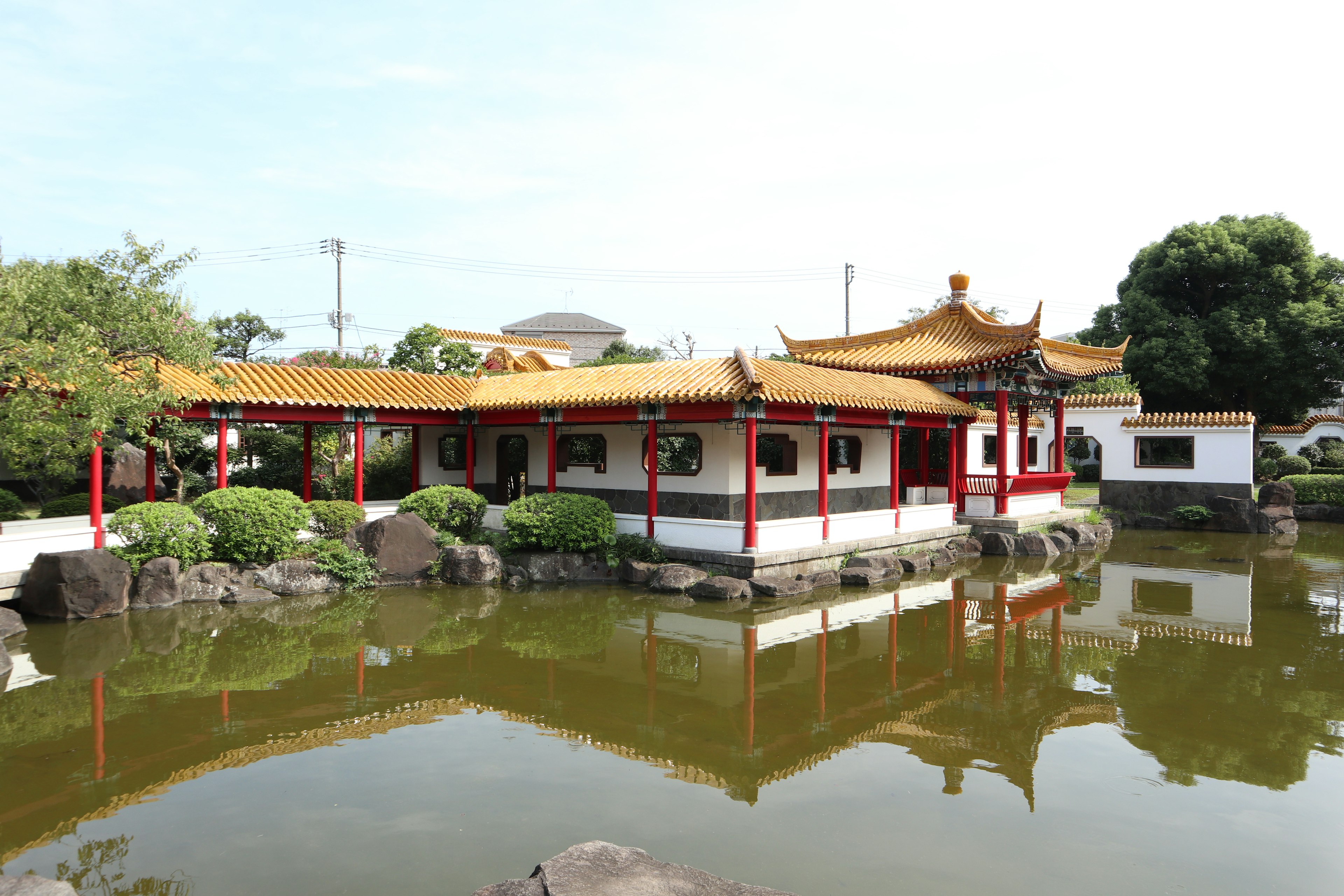 Chinesisches Gebäude mit goldenem Dach, das sich in einem Teich spiegelt