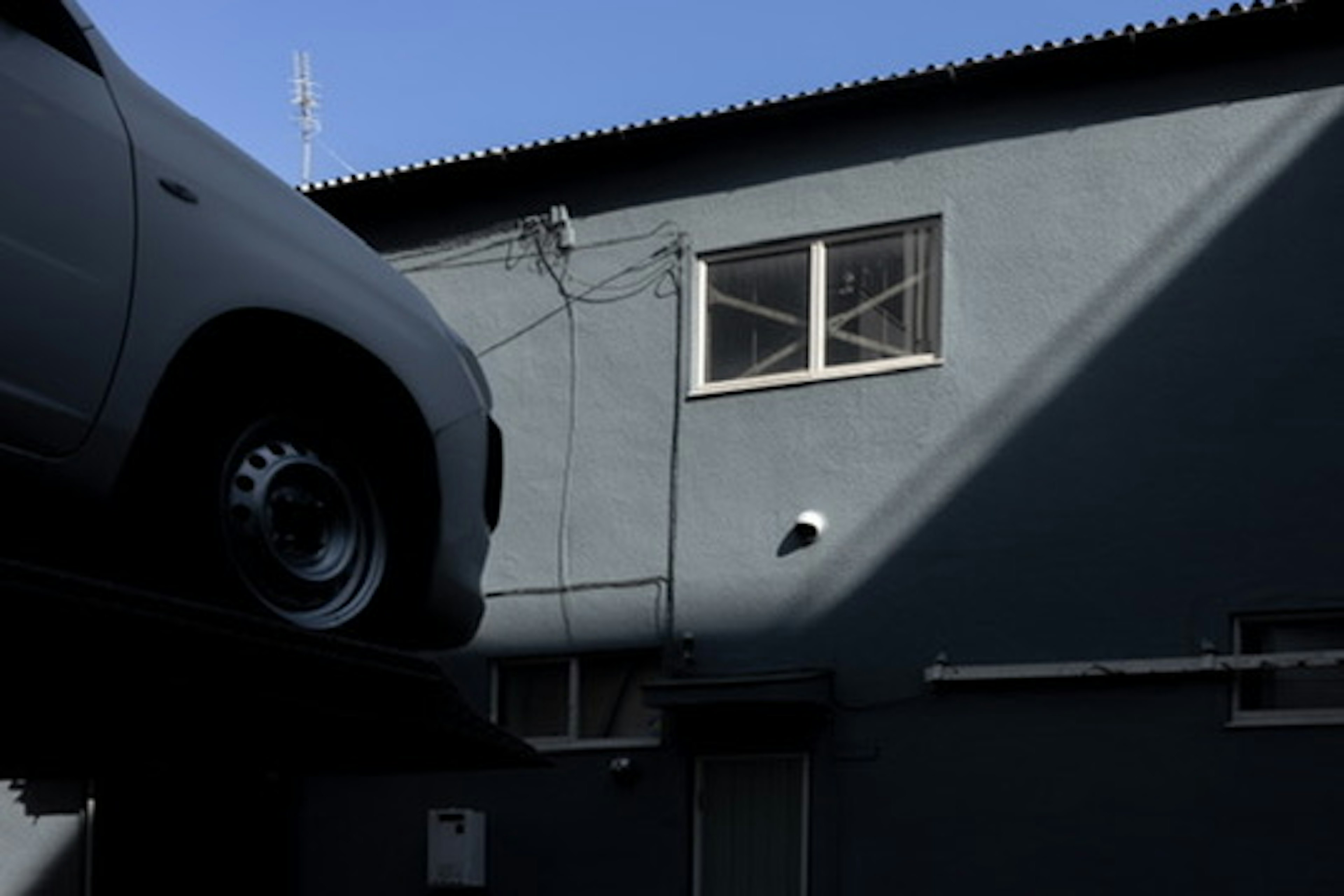 Vista parcial de un edificio de pared azul con un coche blanco