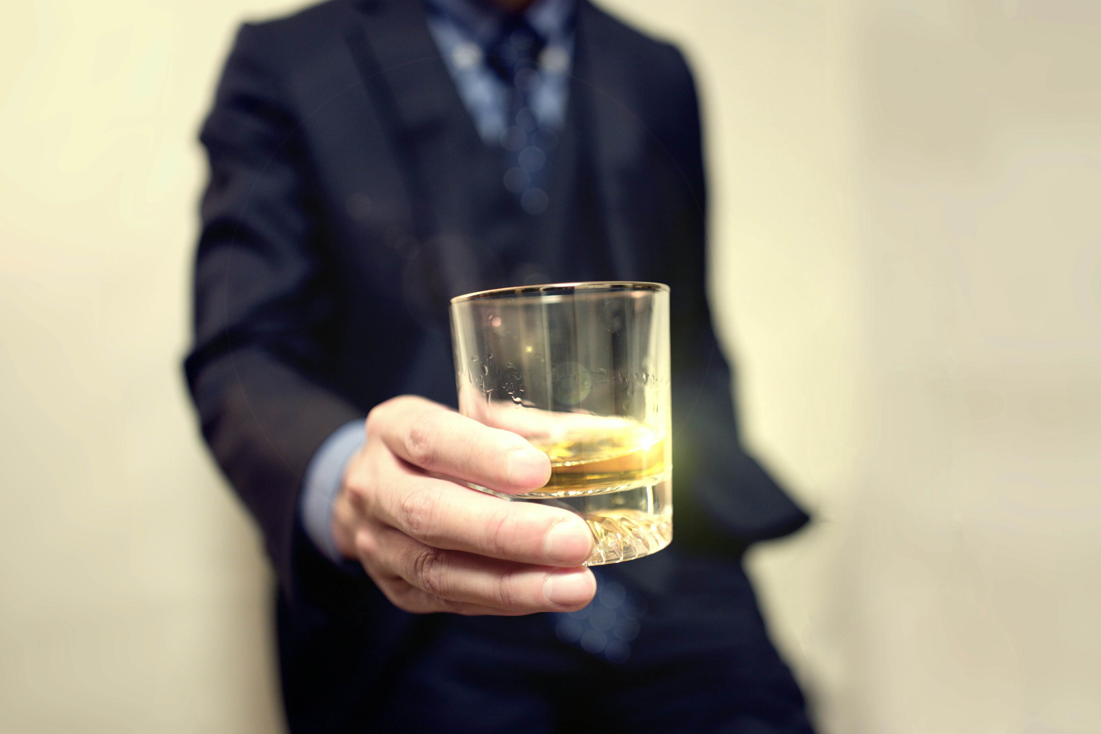 A man in a suit holding a glass of whiskey