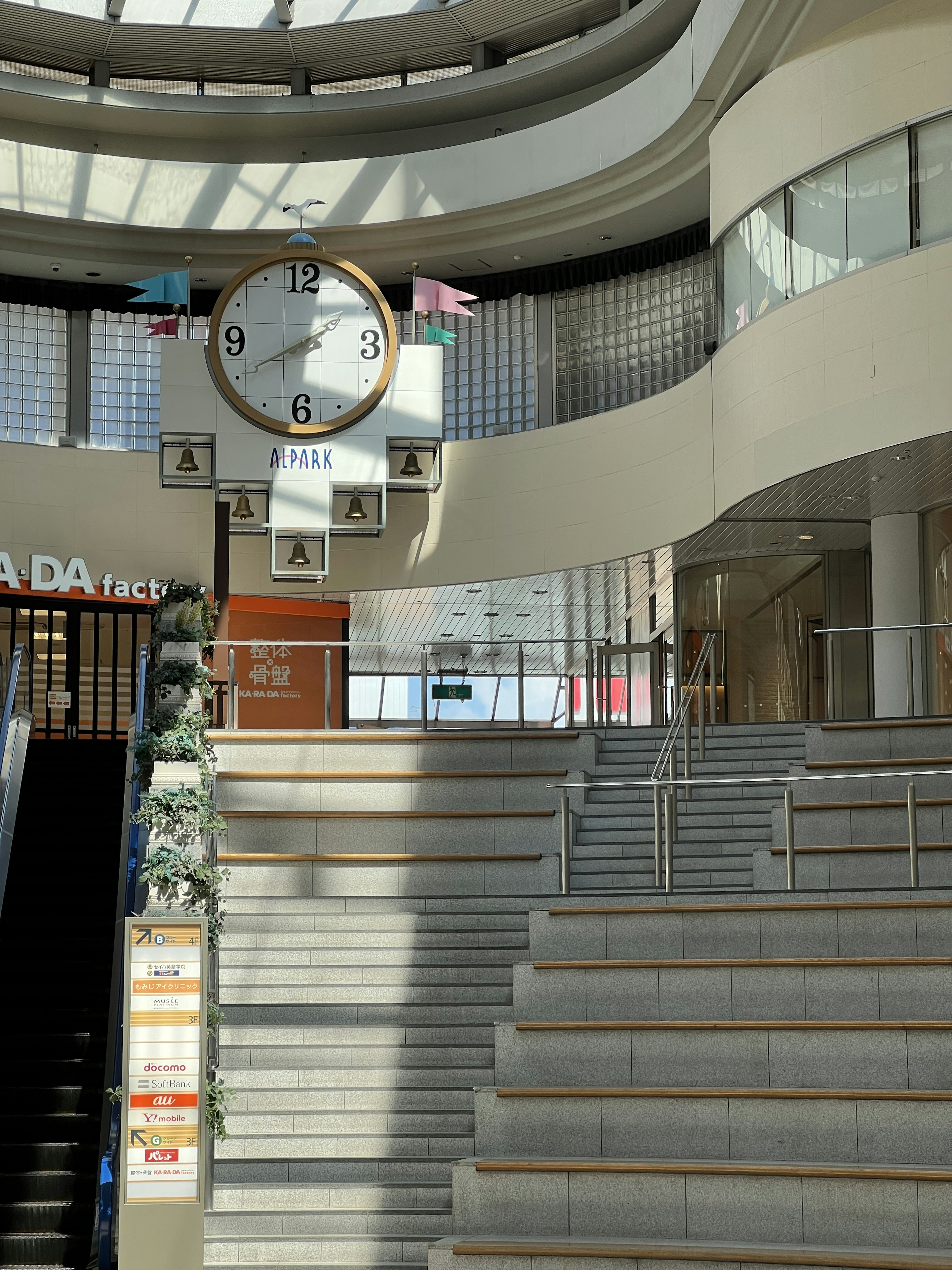 Gran reloj y escaleras en el interior luminoso de un edificio comercial