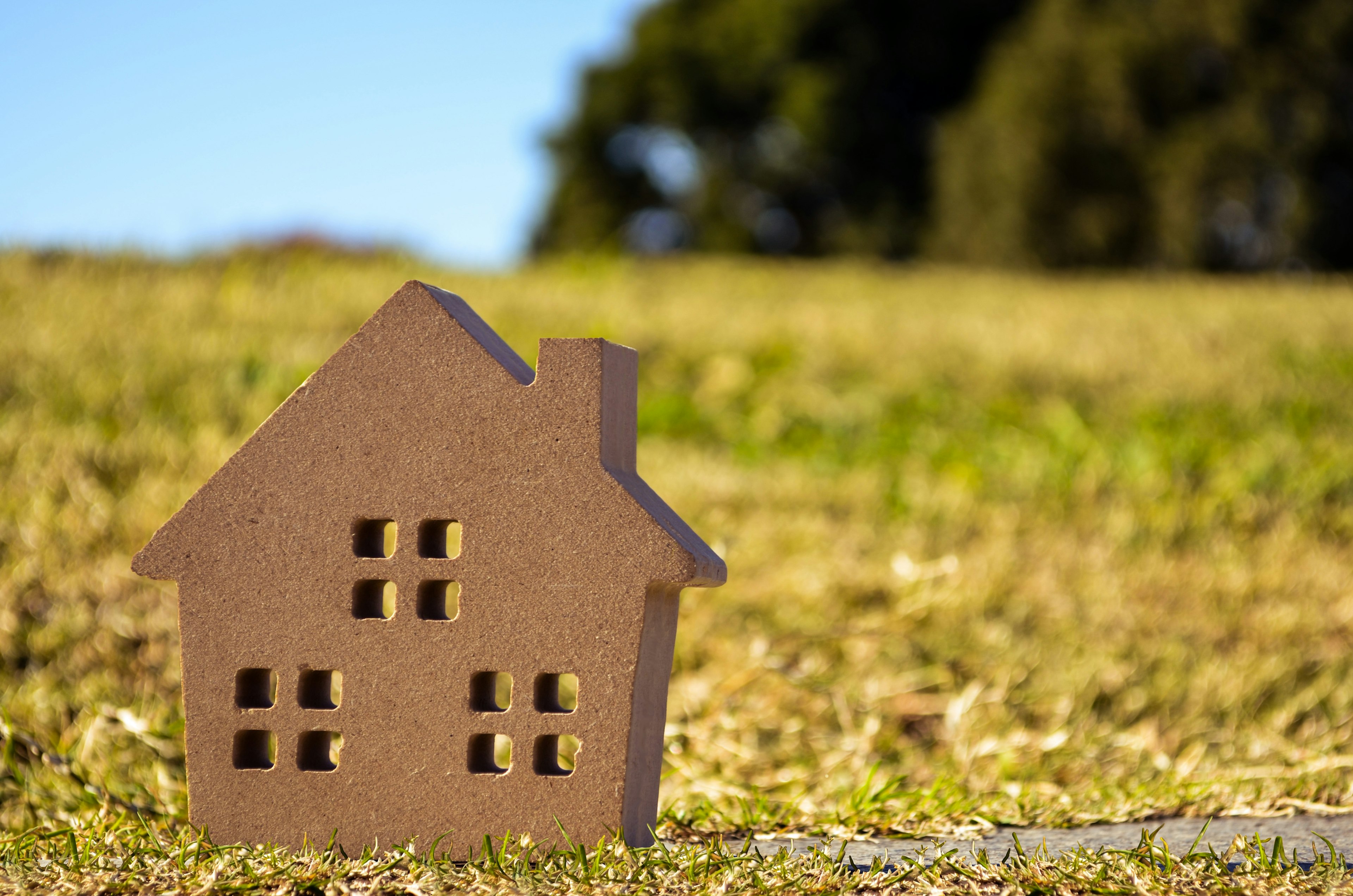 Un petit modèle de maison marron placé sur de l'herbe verte