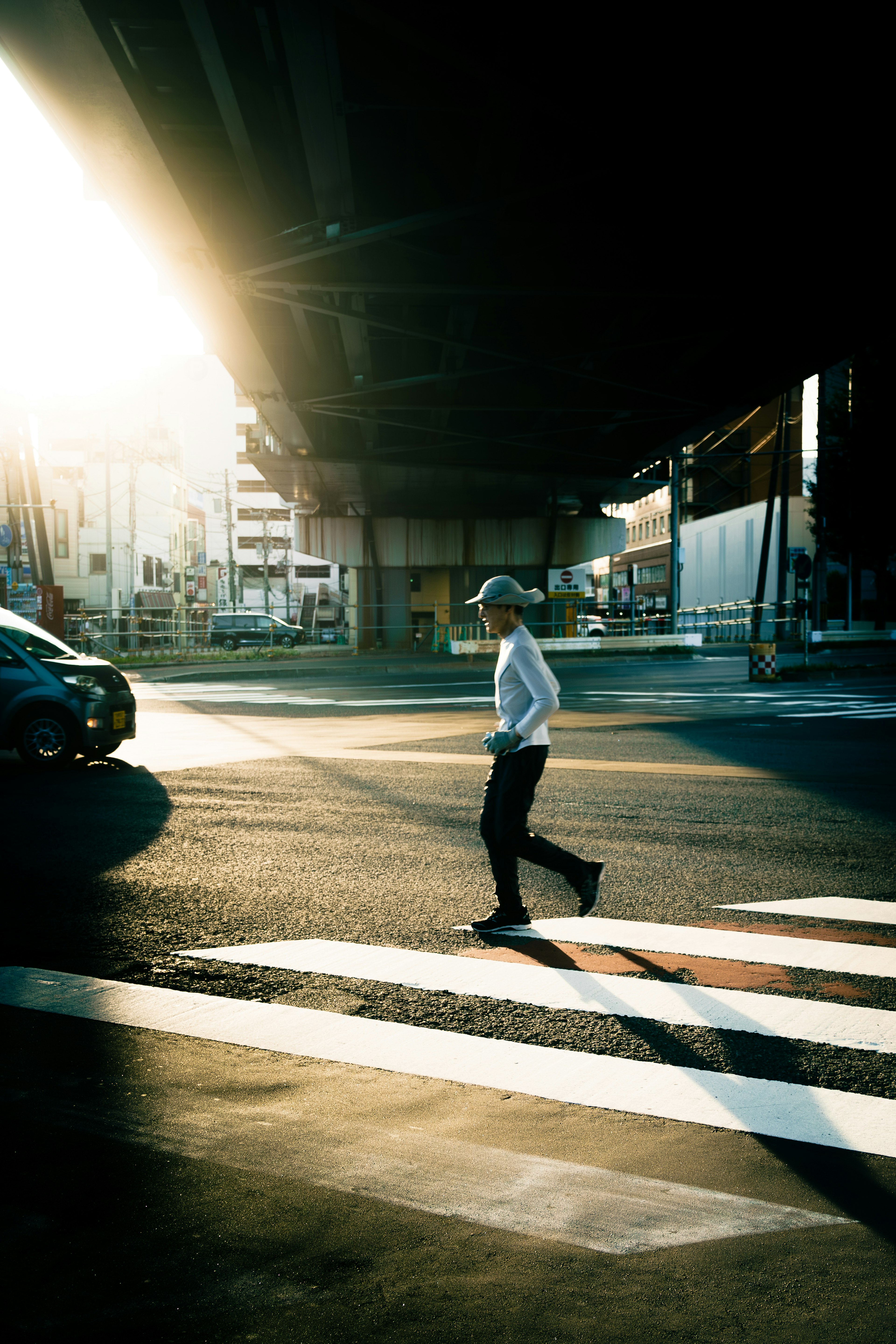 Silhouette of a person walking at a city intersection with sunlight streaming through