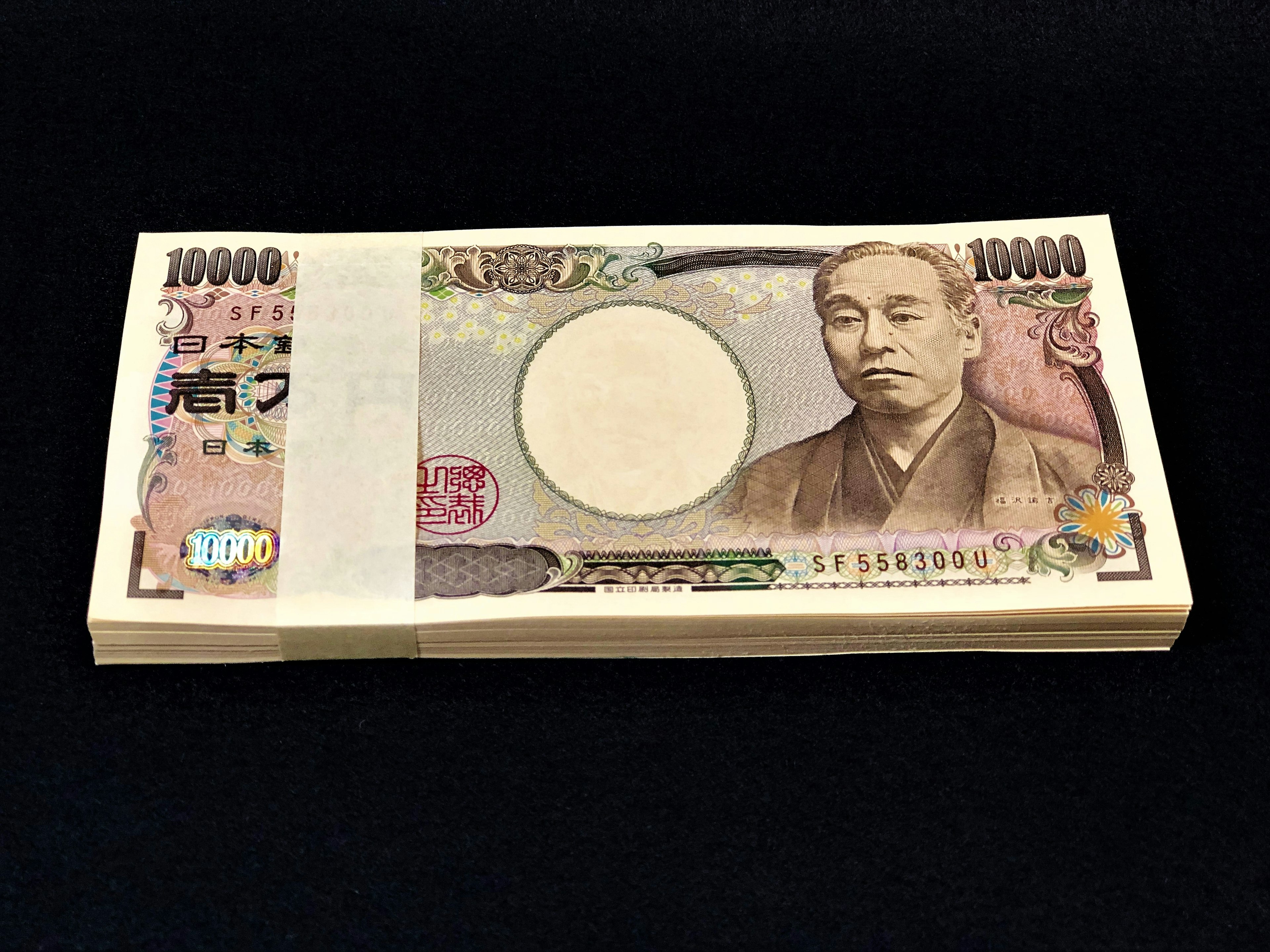 A bundle of 10,000 yen bills placed on a black background