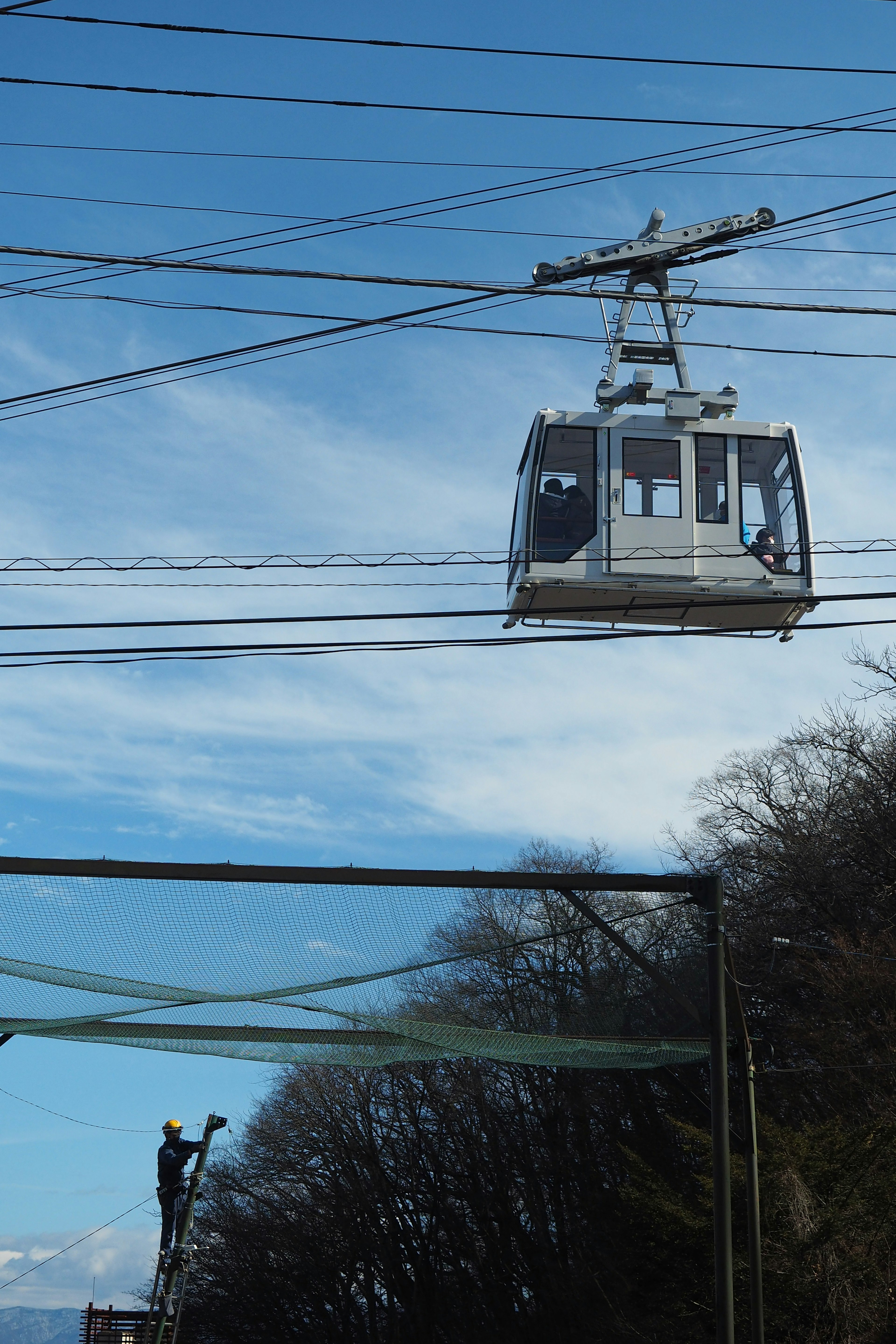 Eine Seilbahn, die am Himmel fährt, mit einem Arbeiter in der Nähe