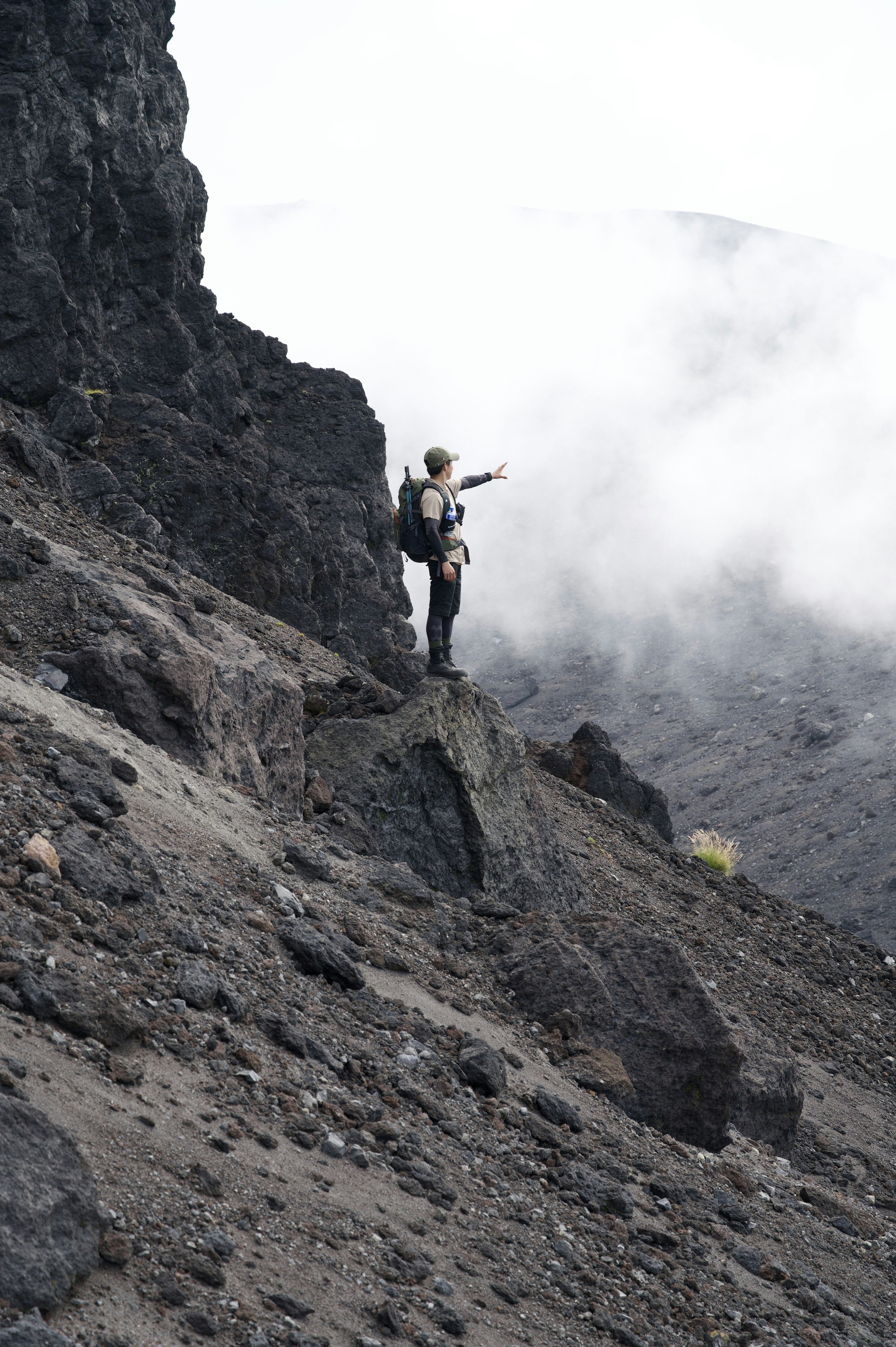 站在火山斜坡上的徒步旅行者指向远方