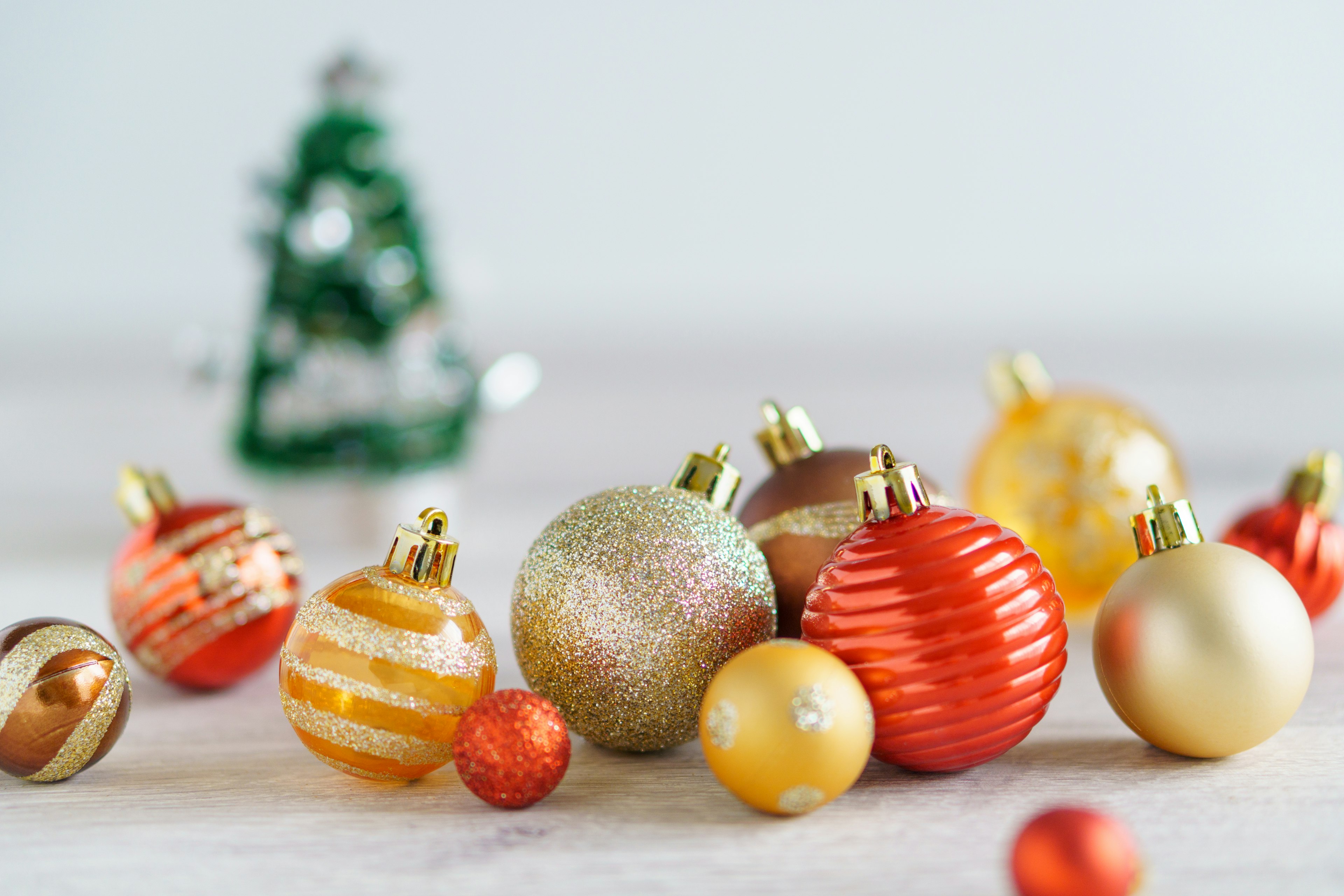 Bunte Weihnachtsornamente mit einem kleinen Baum im Hintergrund