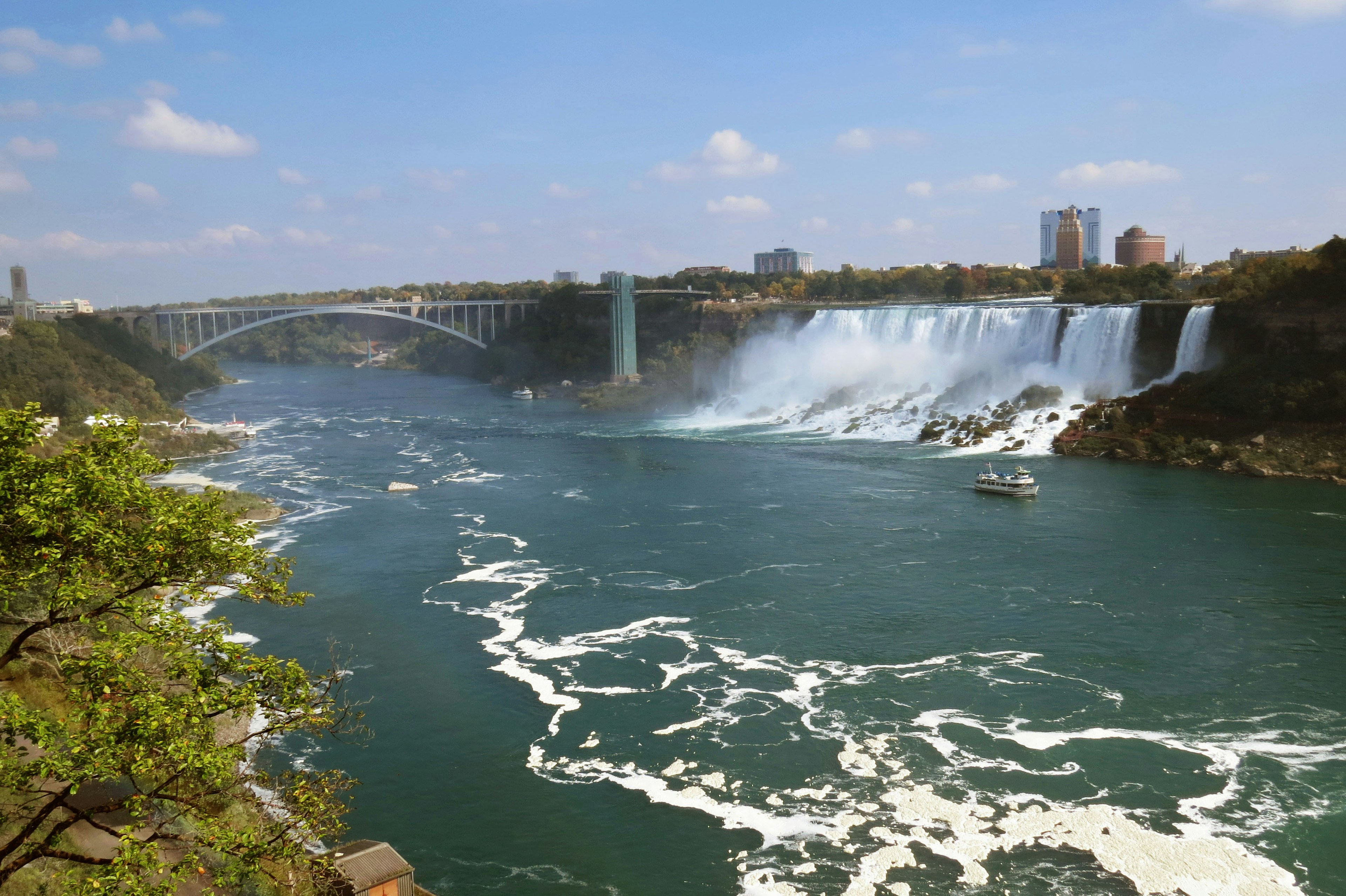 Pemandangan menakjubkan dari Air Terjun Niagara dengan langit biru cerah dan pepohonan hijau subur