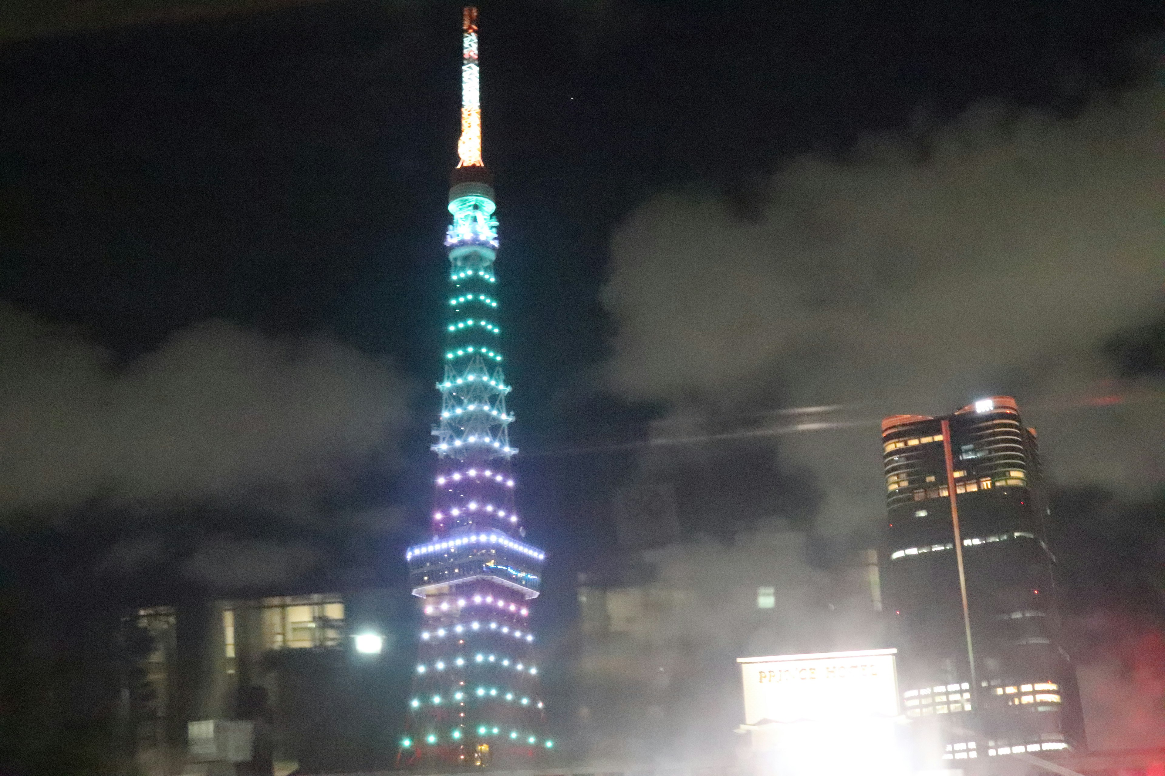 Tokyo Tower at night with colorful lights and cloudy sky