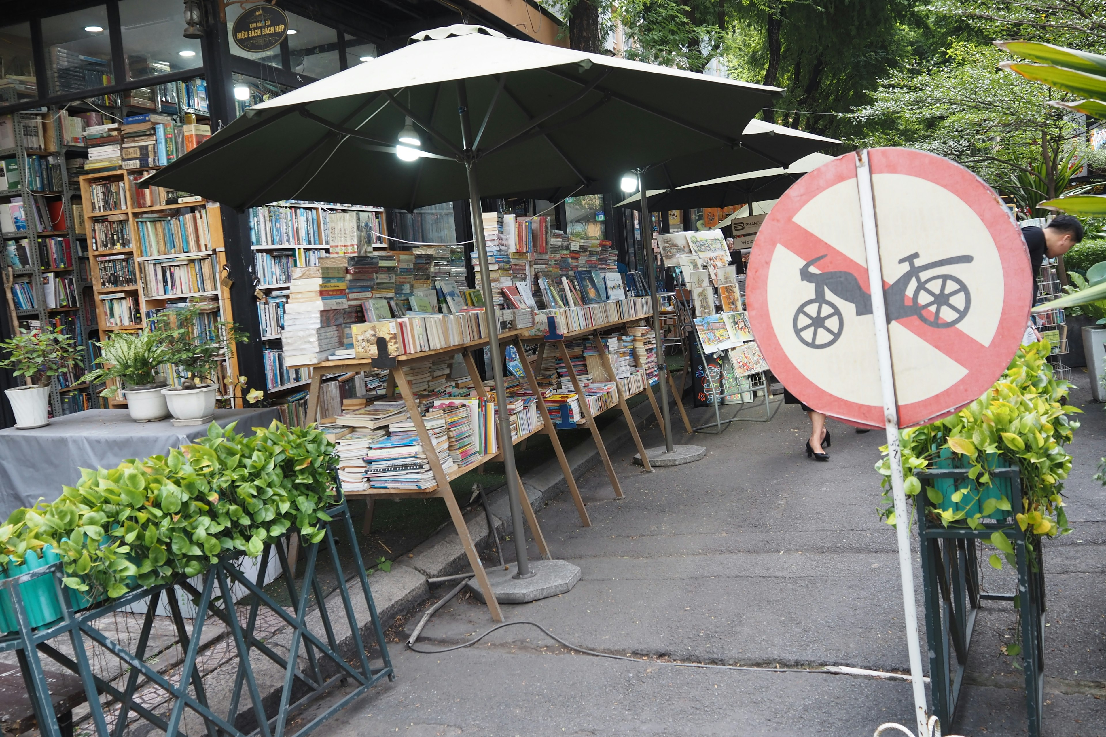 Librería con estantes de libros al aire libre y señal de no bicicletas