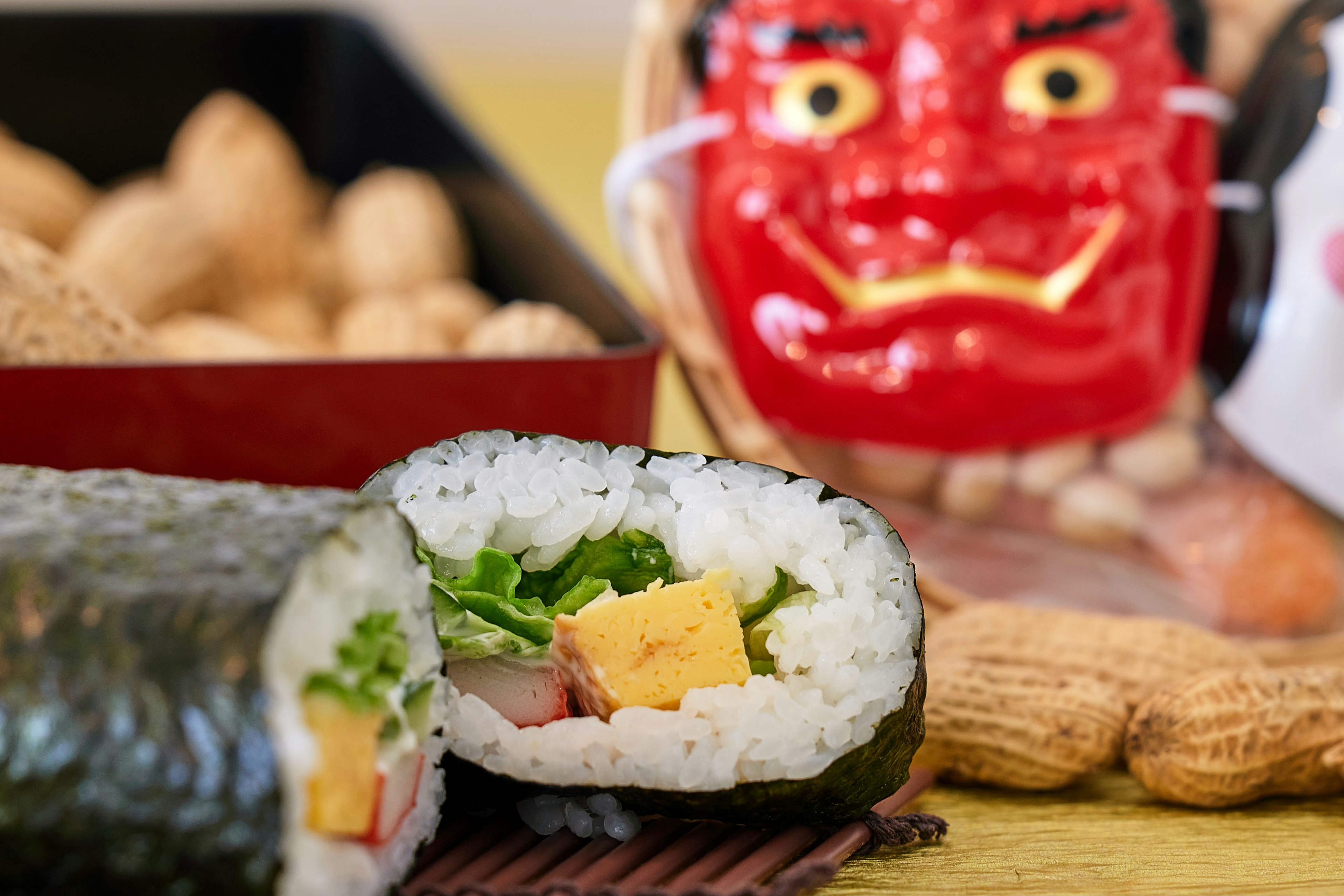 Sushirolle mit Gemüse und Ei neben einer roten Dämonmaske