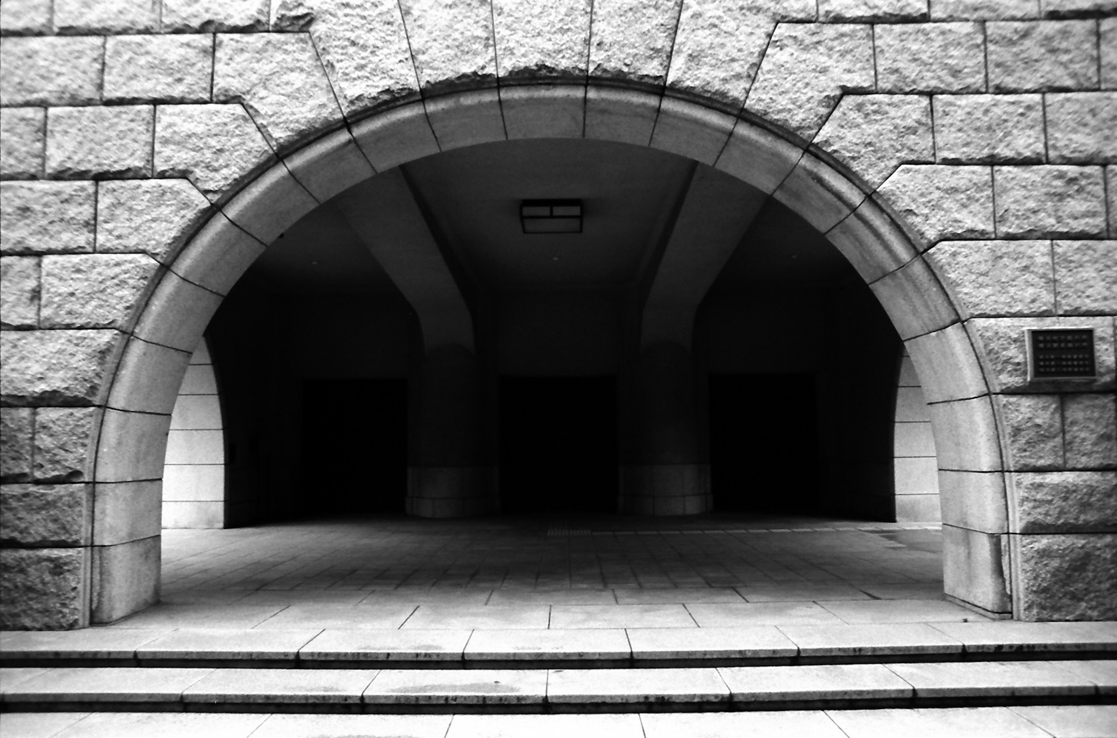 Entrée en arc avec des murs en pierre menant à un passage sombre