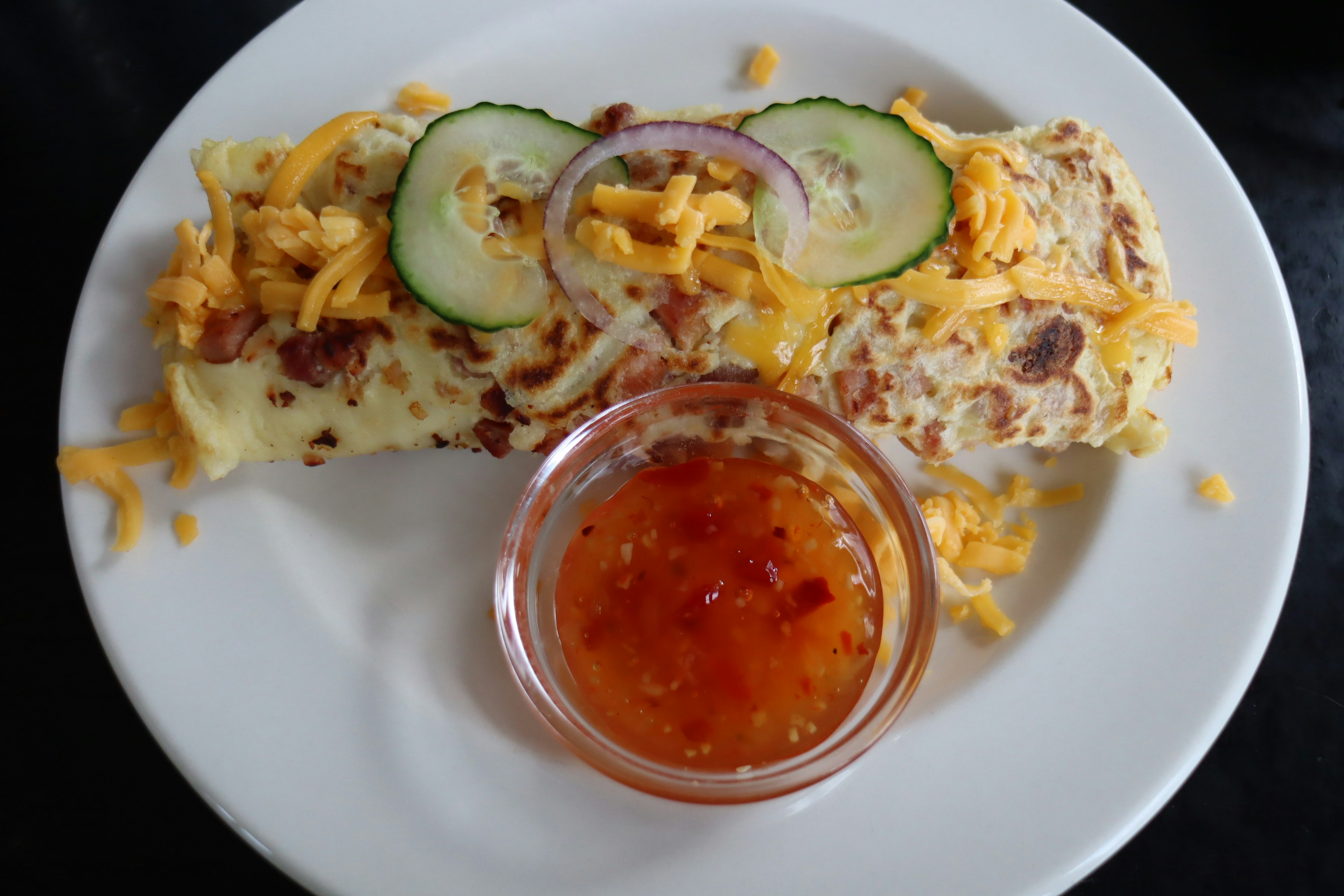 Omelette garnie de fromage et de concombre accompagnée de sauce chili douce