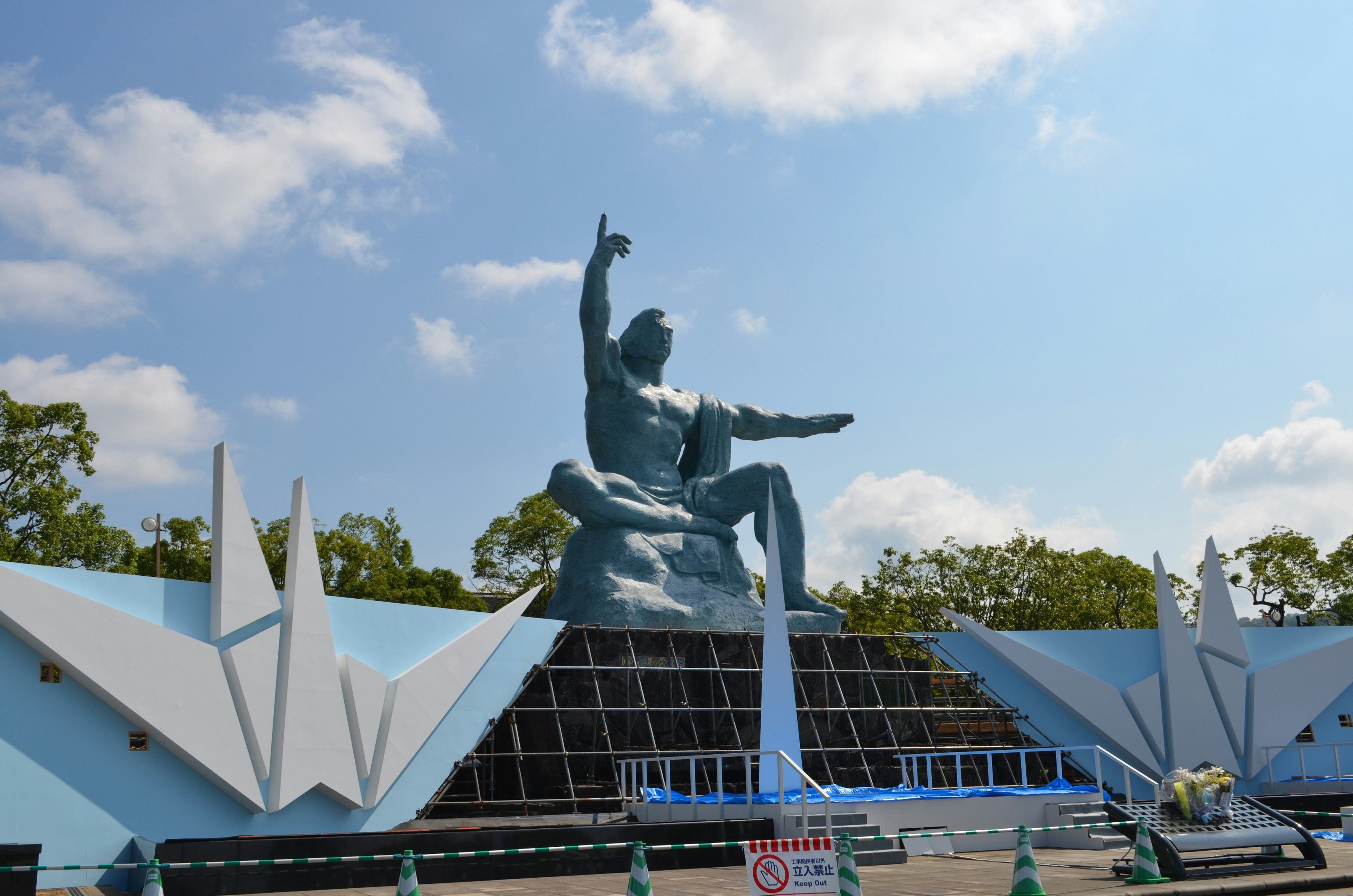 Une grande statue assise devant un fond bleu avec un bras levé