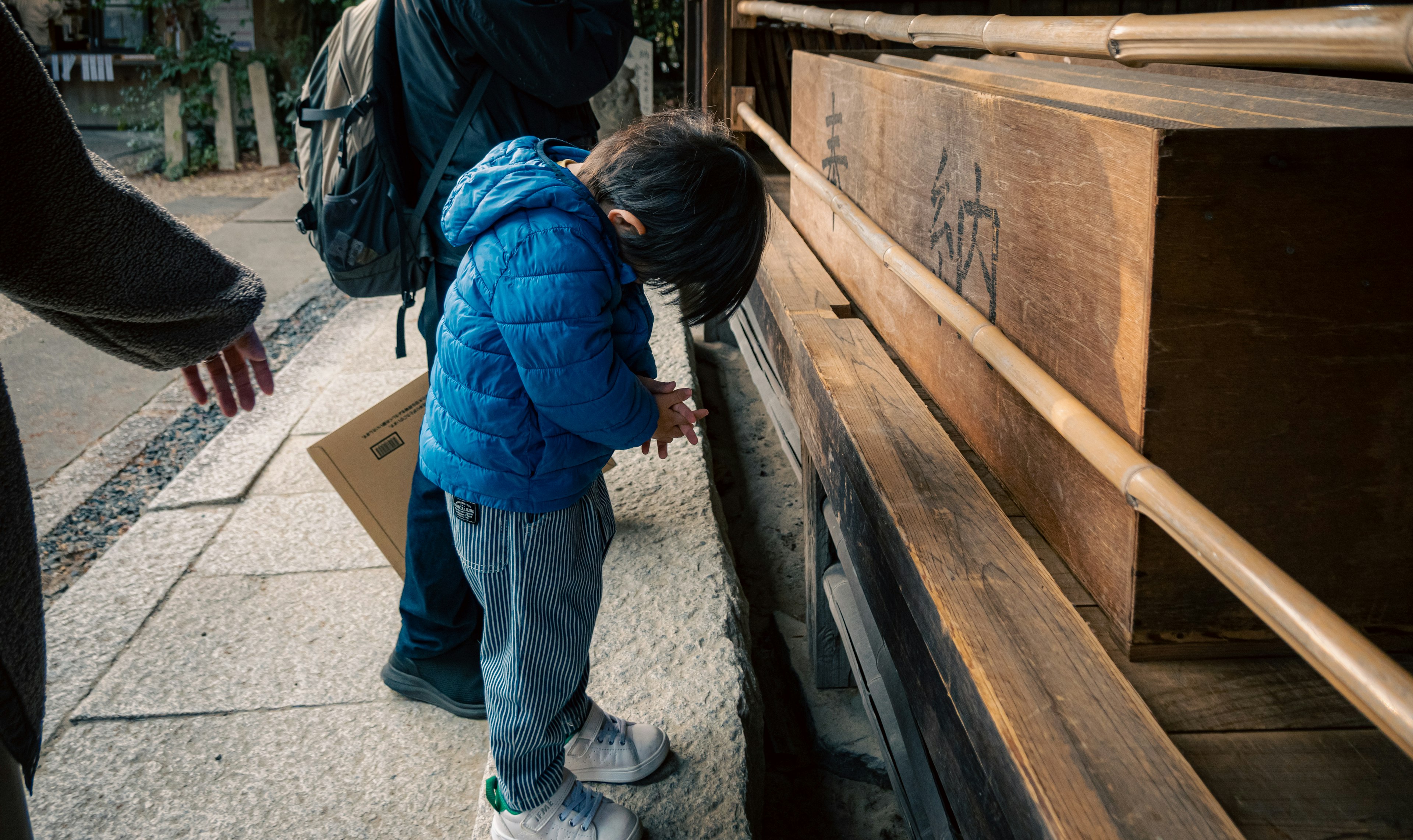 Ein Kind in blauer Jacke, das eine Holzstruktur beobachtet