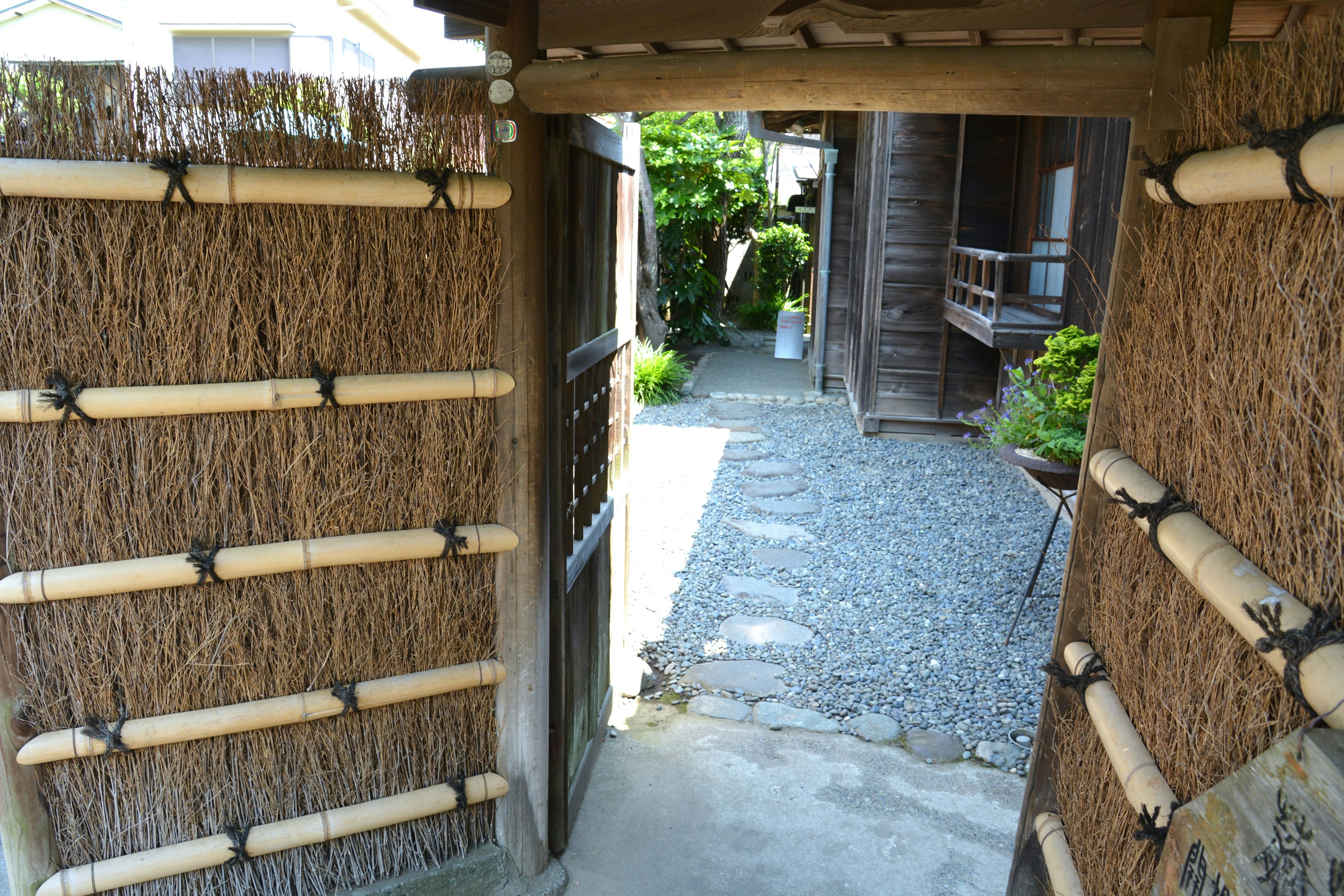 Pemandangan melalui gerbang tradisional Jepang dengan tanaman hijau dan jalan berbatu