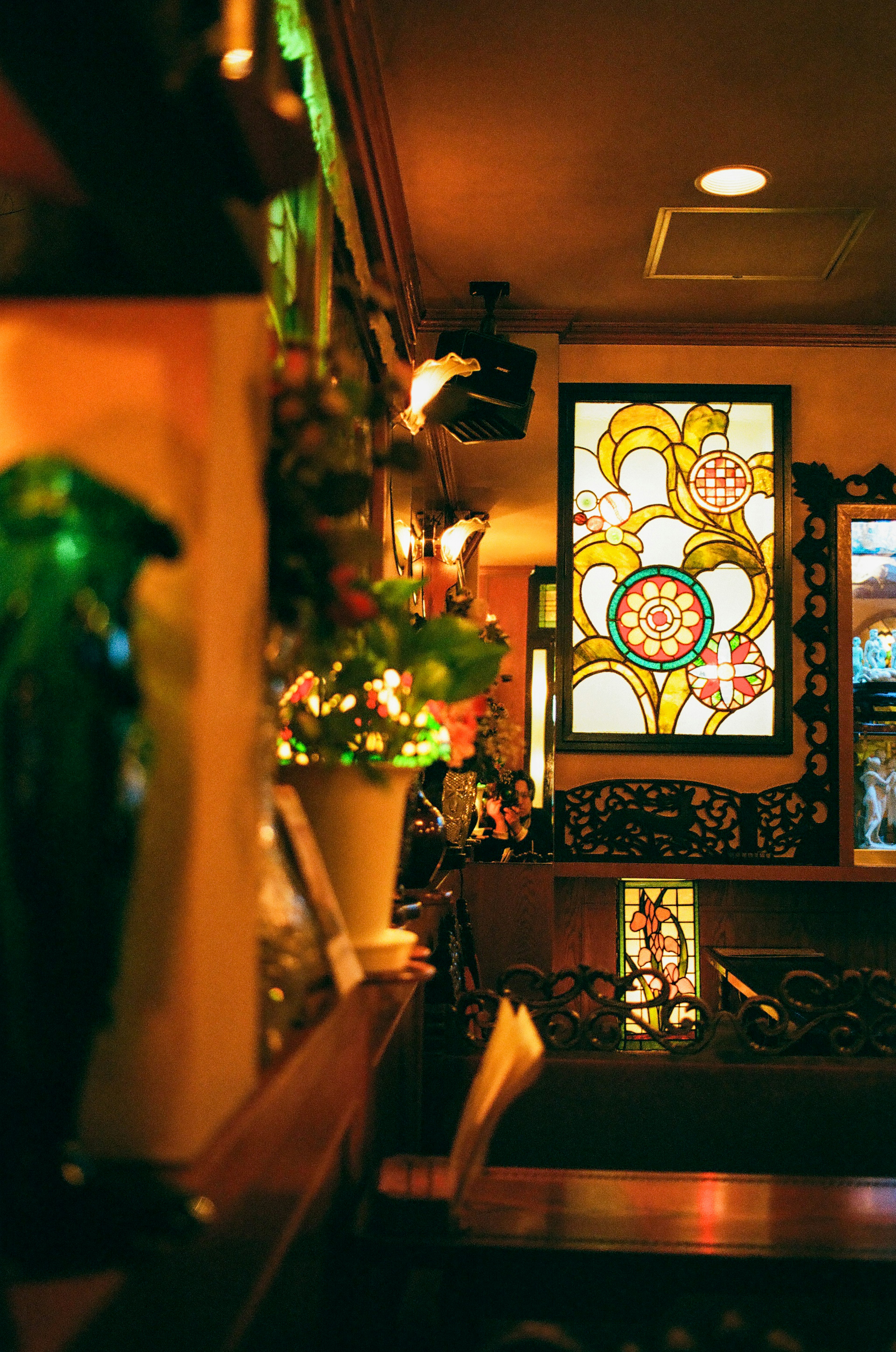 Interior de una cafetería con vitrales coloridos y plantas