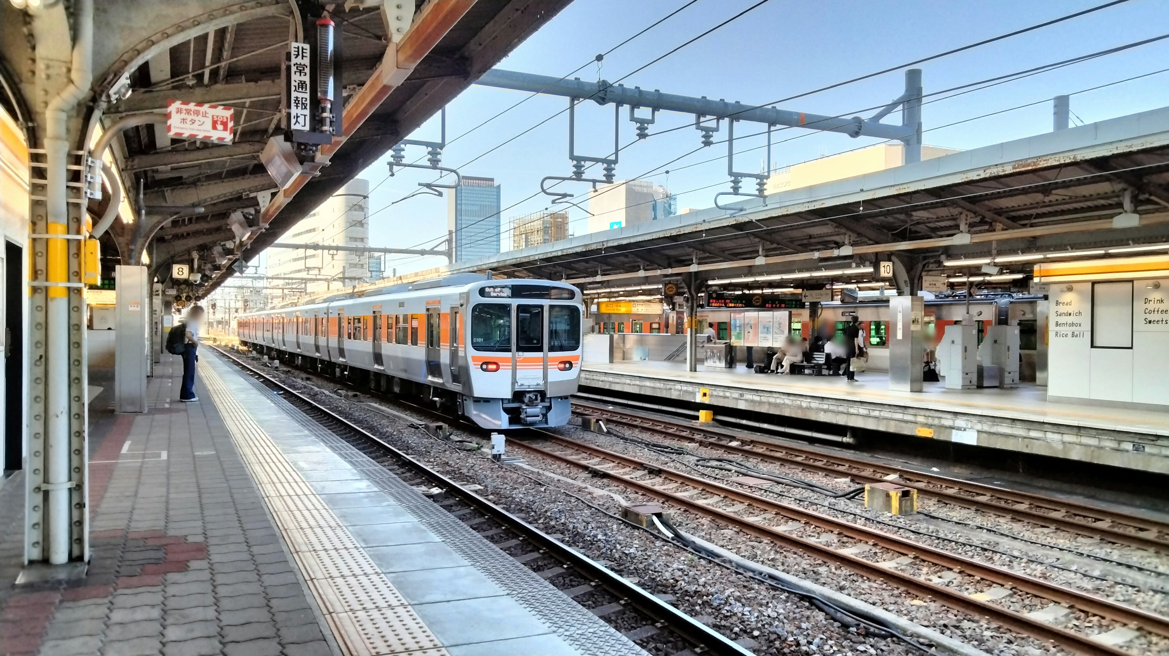 Train stopped at a station platform with surrounding buildings