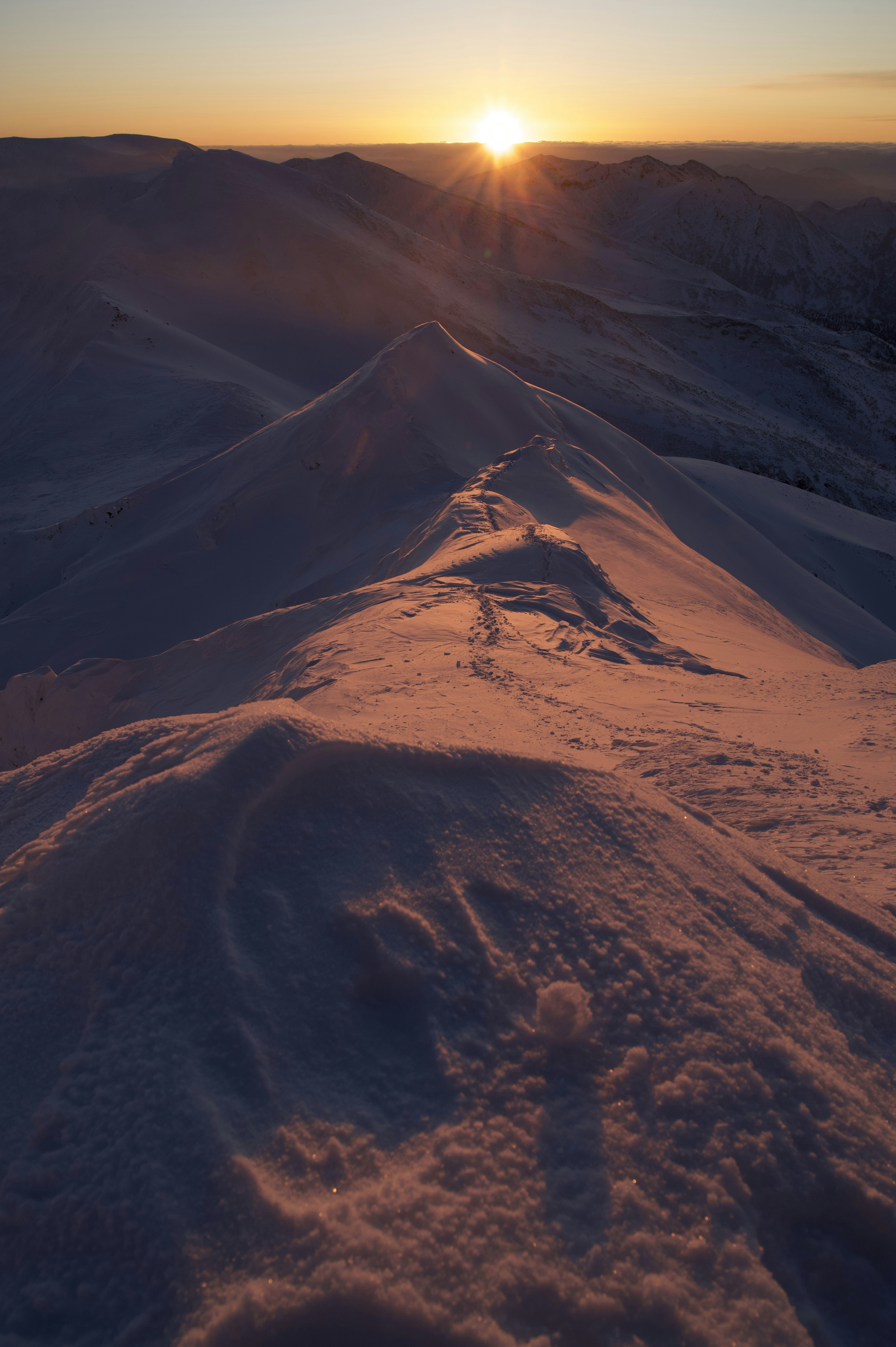 Crête de montagne enneigée avec un coucher de soleil