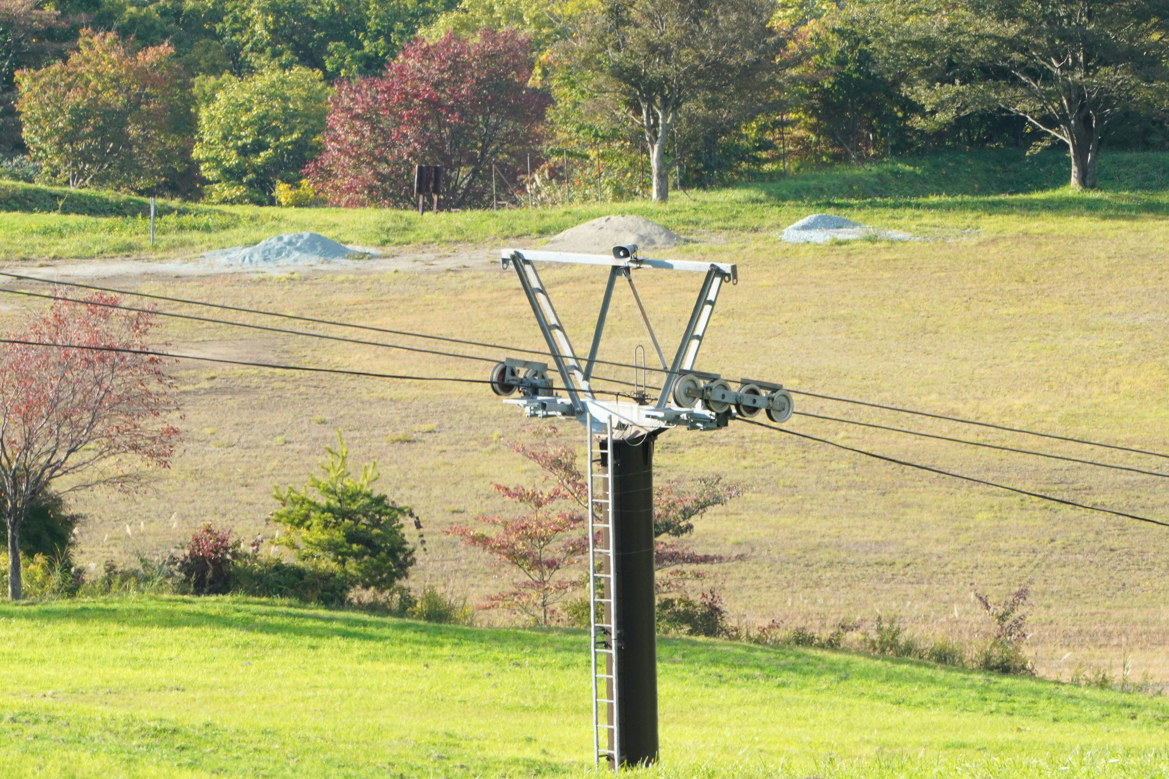 Lift support tower with cables in a green meadow