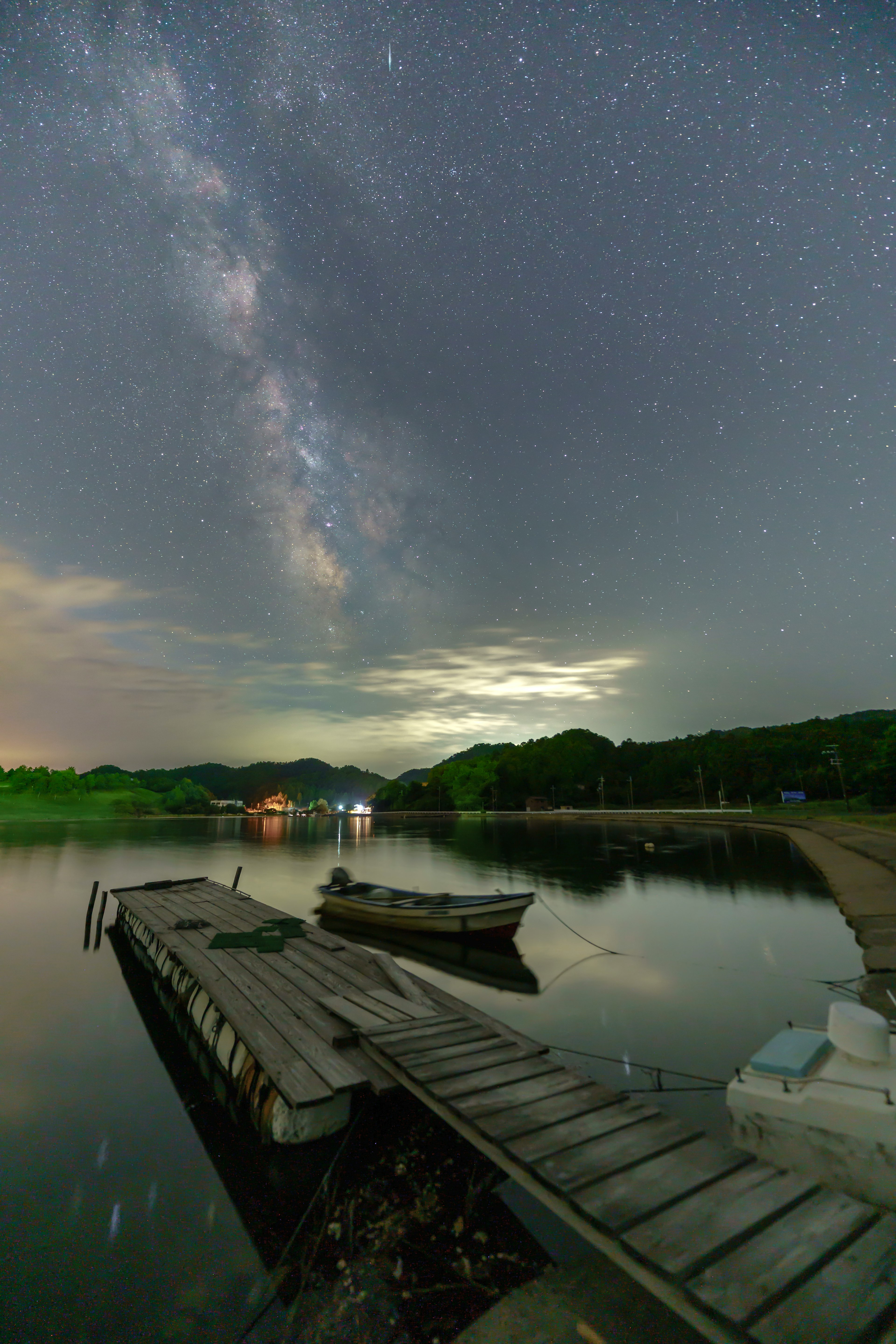 星空とミルキーウェイが映る静かな湖の風景とボート