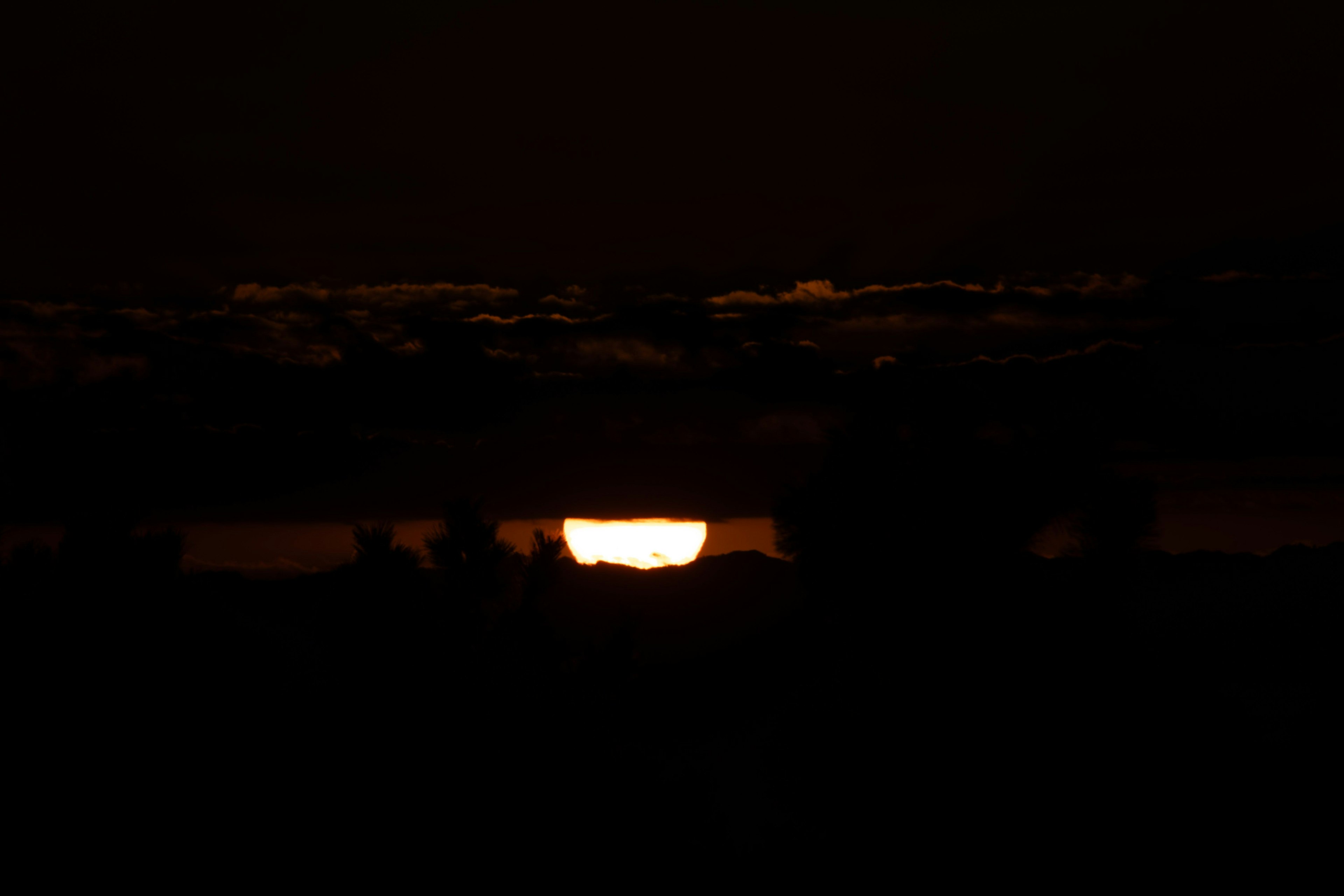 暗い空に沈む夕日のシルエット
