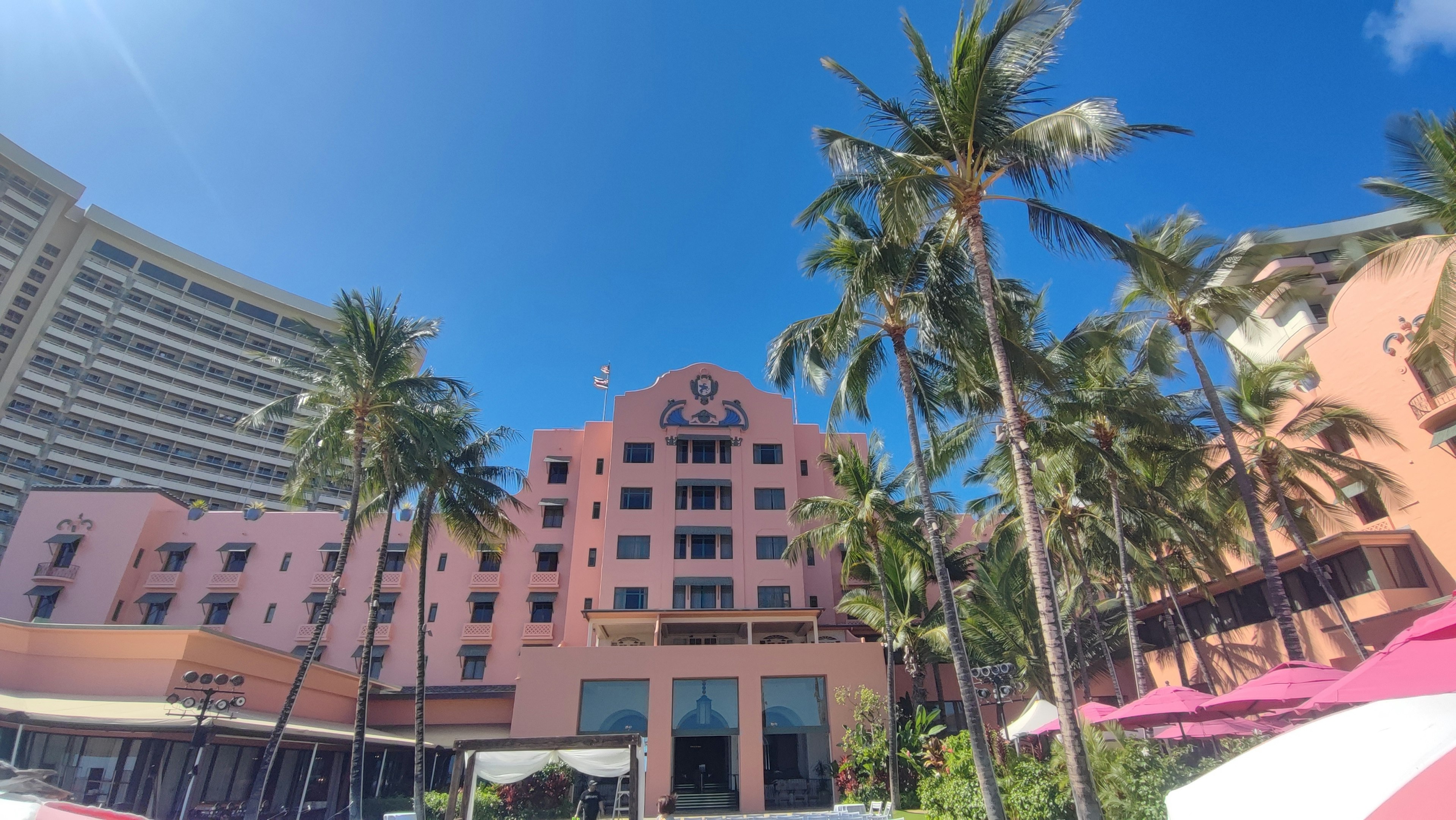 Ein rosa Hotel umgeben von Palmen unter einem klaren blauen Himmel