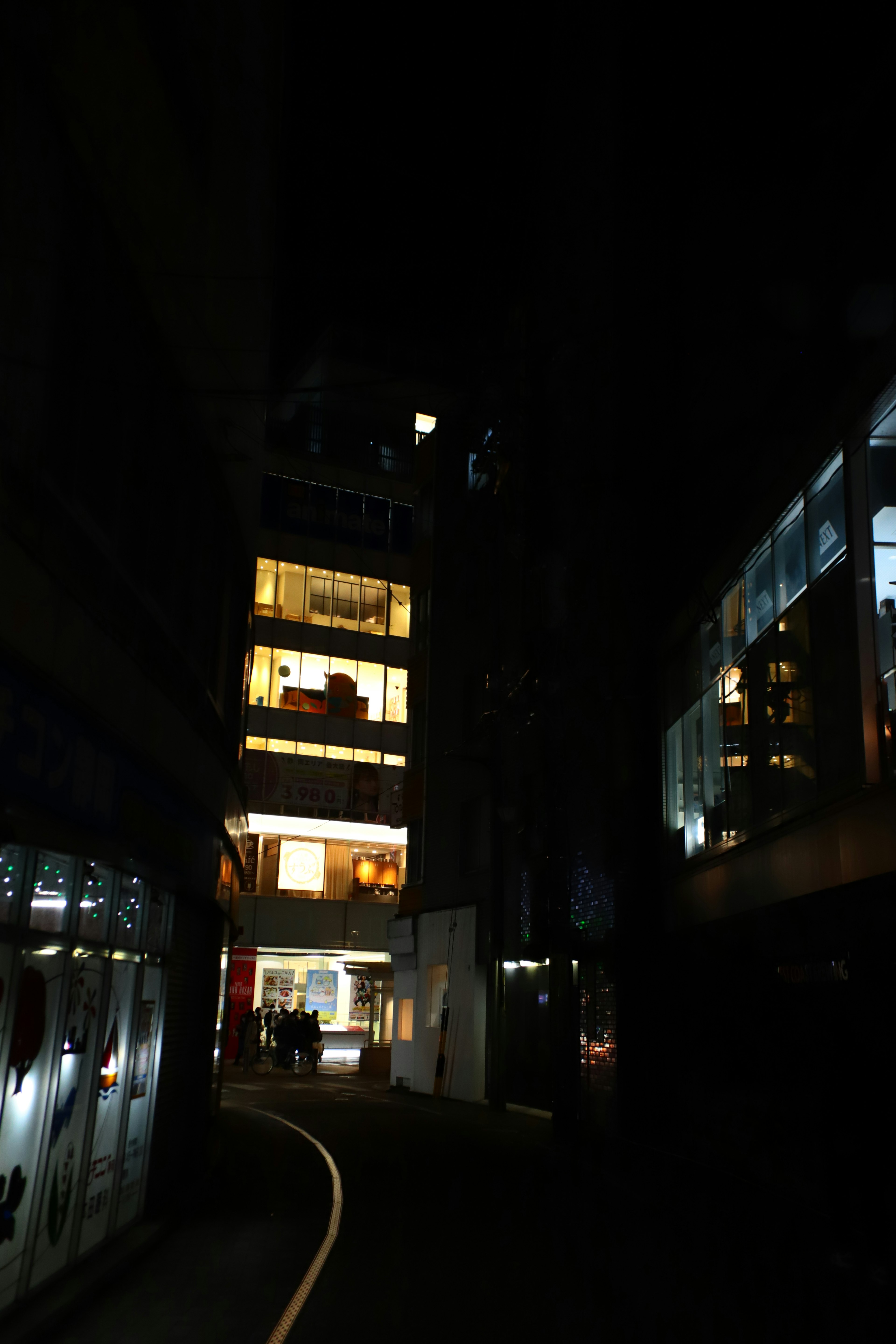 Illuminated buildings along a narrow street at night